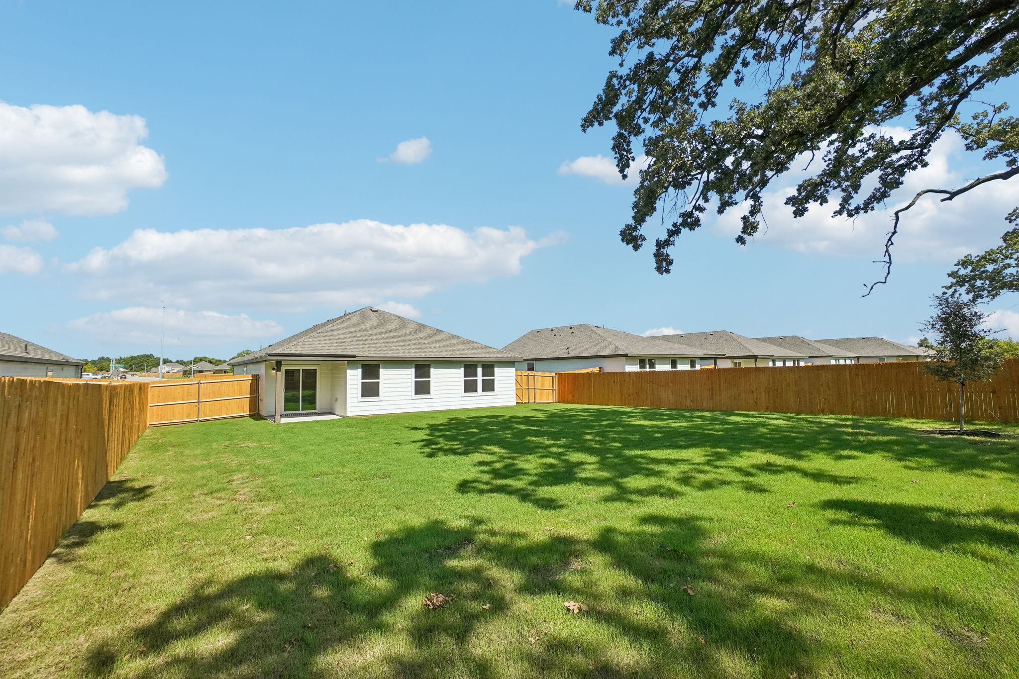 A grassy yard with a fence and a house in the background.