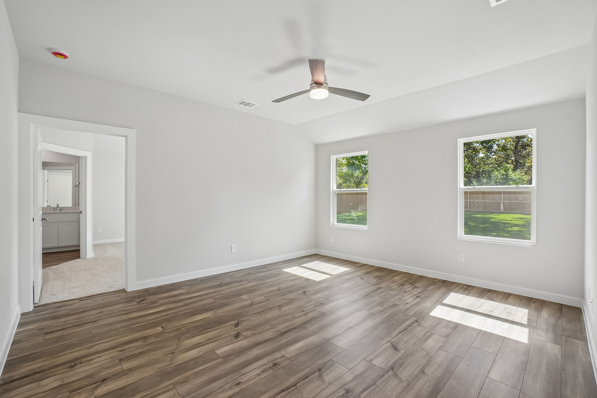 A room with a wood floor and a ceiling fan.