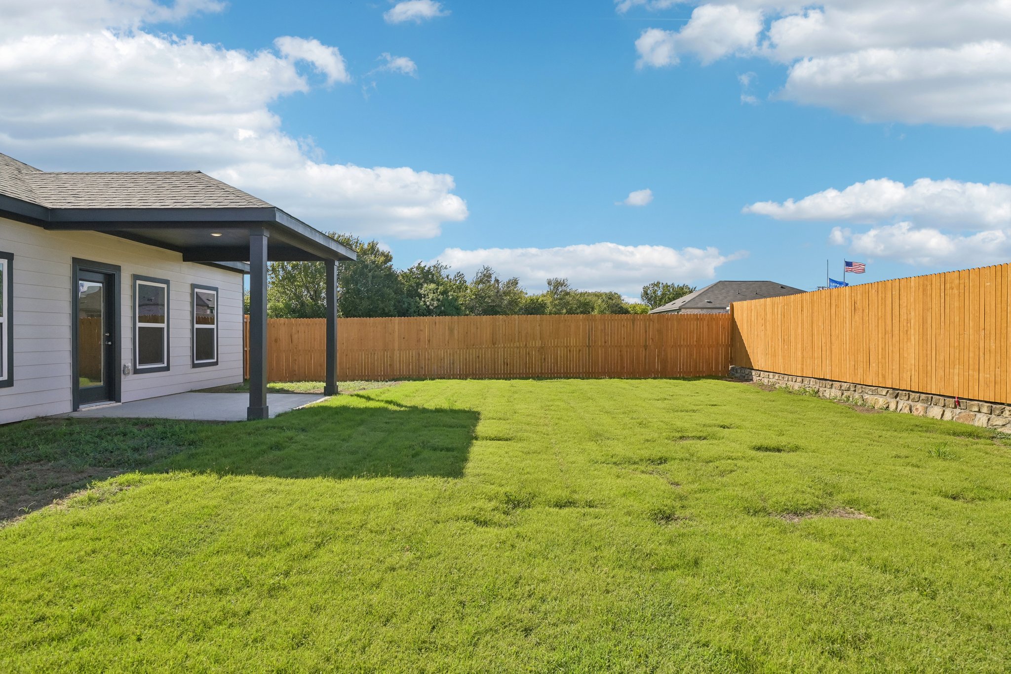 A fenced in yard with a house and a building in the background.