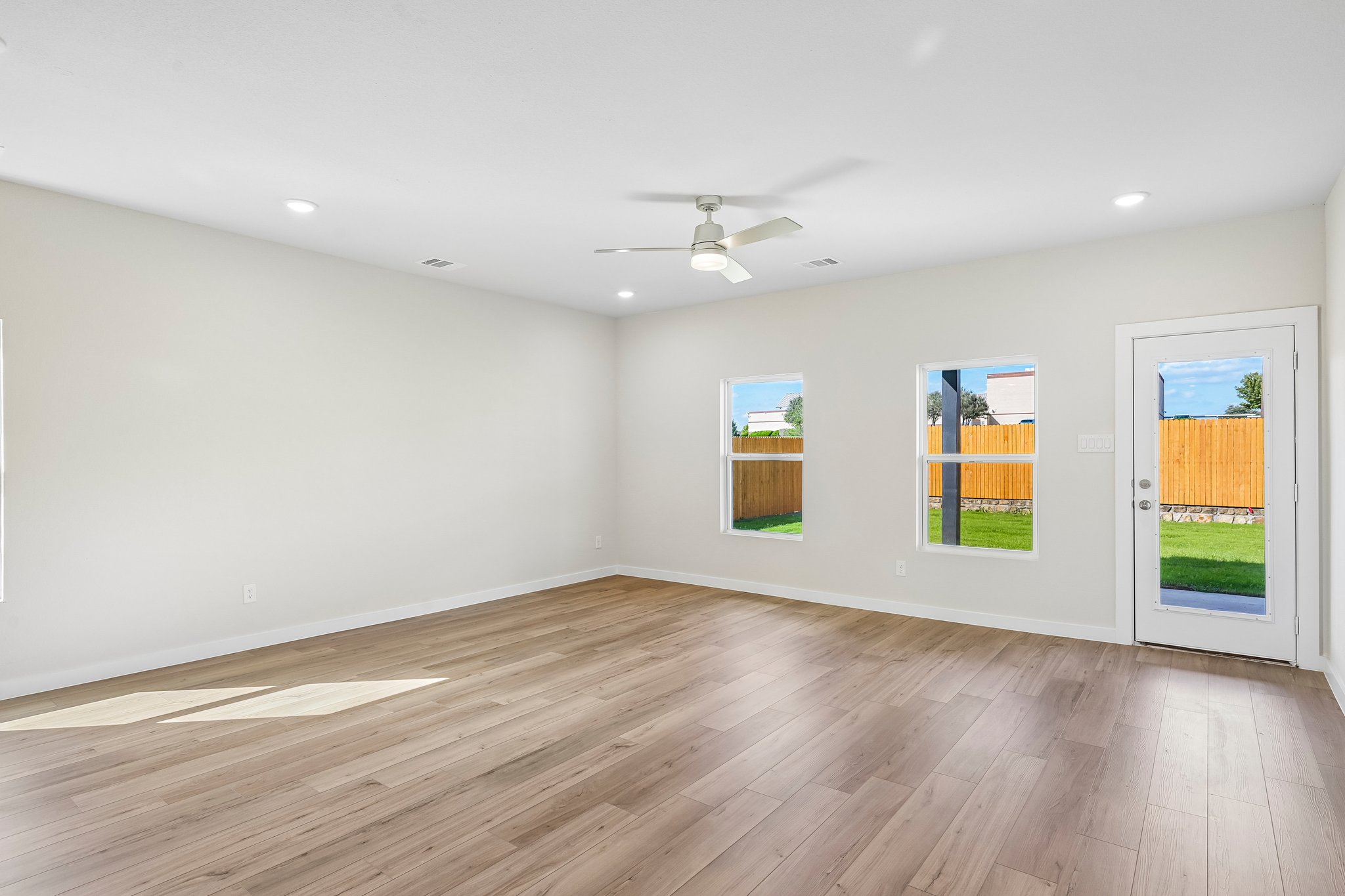 A room with a wood floor and a ceiling fan and a wood floor.