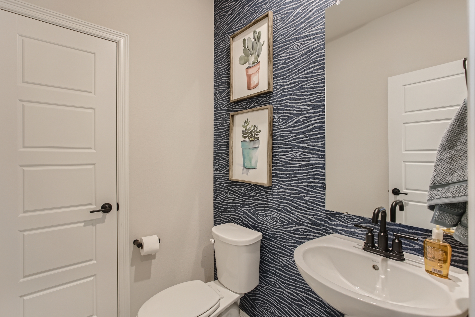 A bathroom with a sink toilet and a mirror.