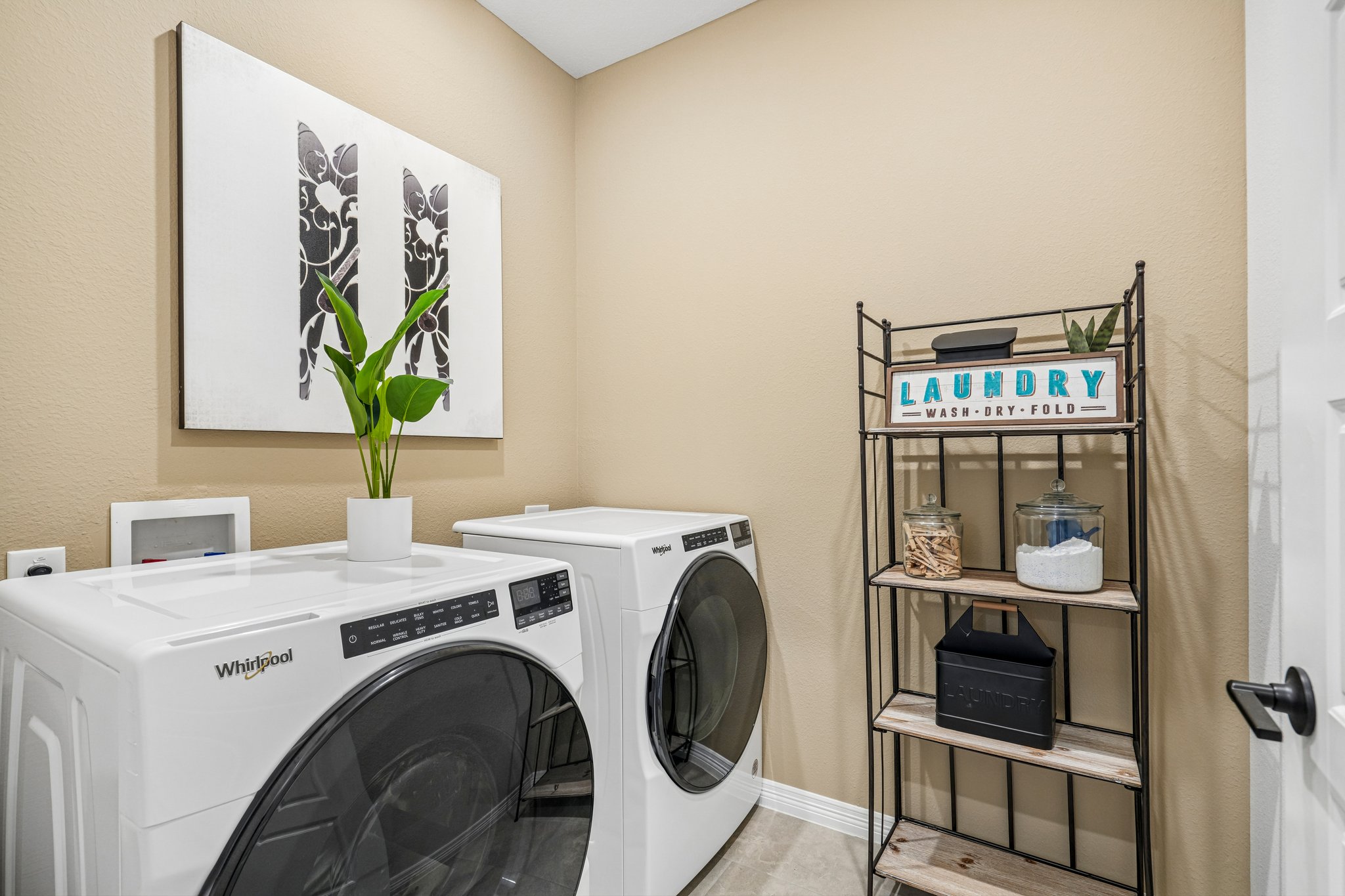 A laundry room with a white washing machine and a shelf with laundry.