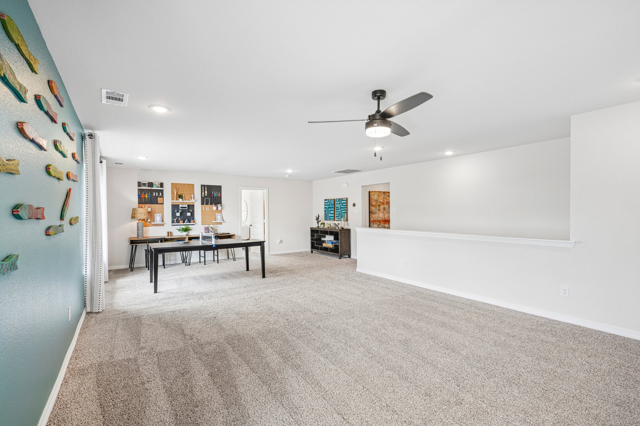 A large room with a table and a ceiling fan.