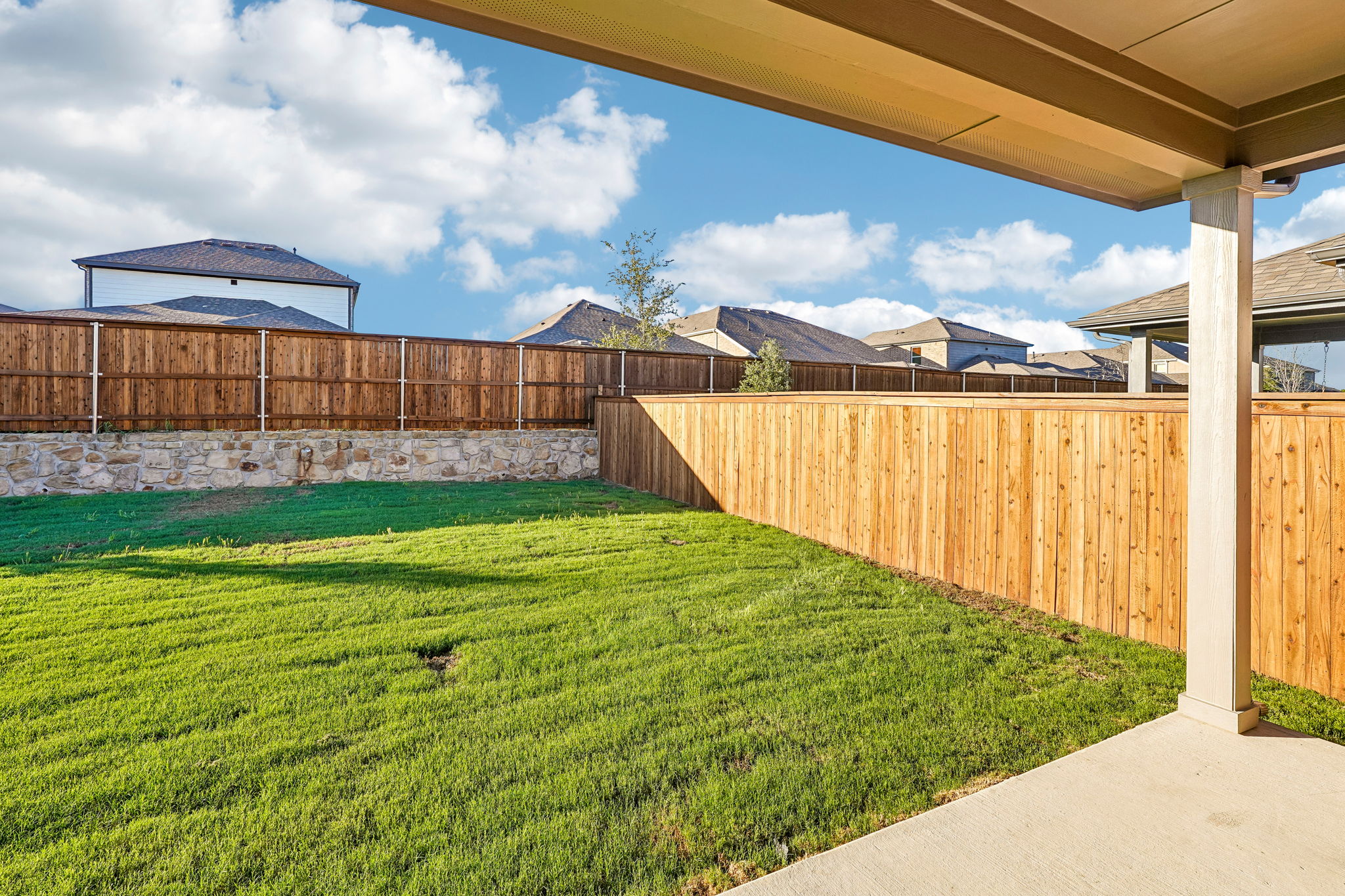 A fenced in yard with a wood fence and a building in the background.