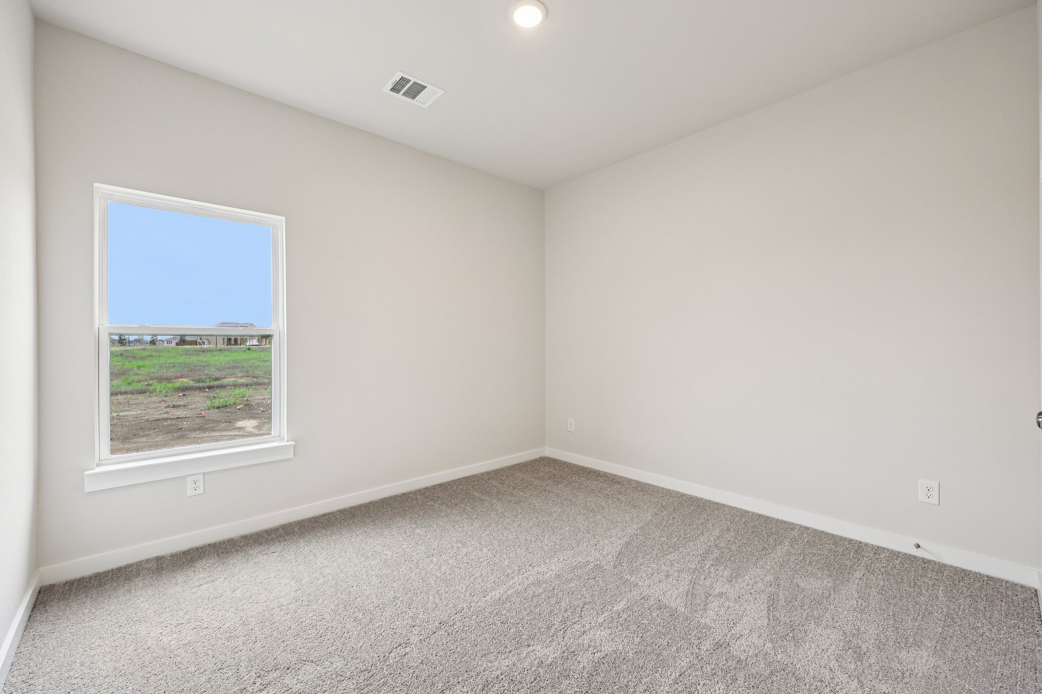 A room with a window and a view of a field.