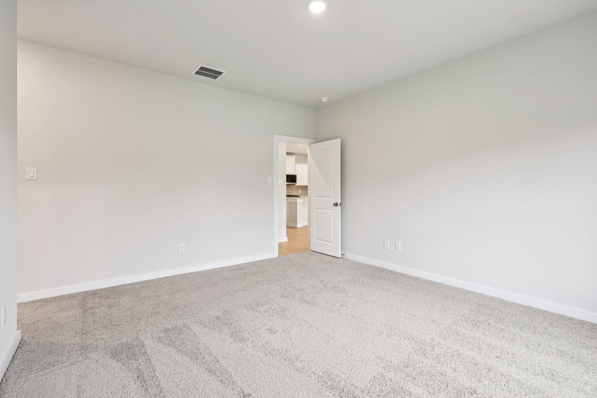 A room with a carpet and a white wall.