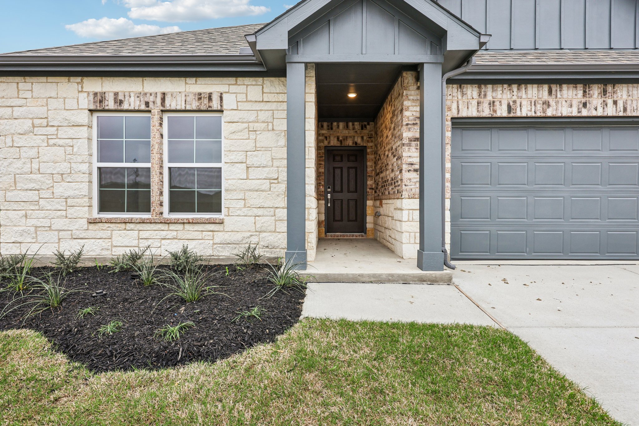 A house with a garage and a lawn in front of it.