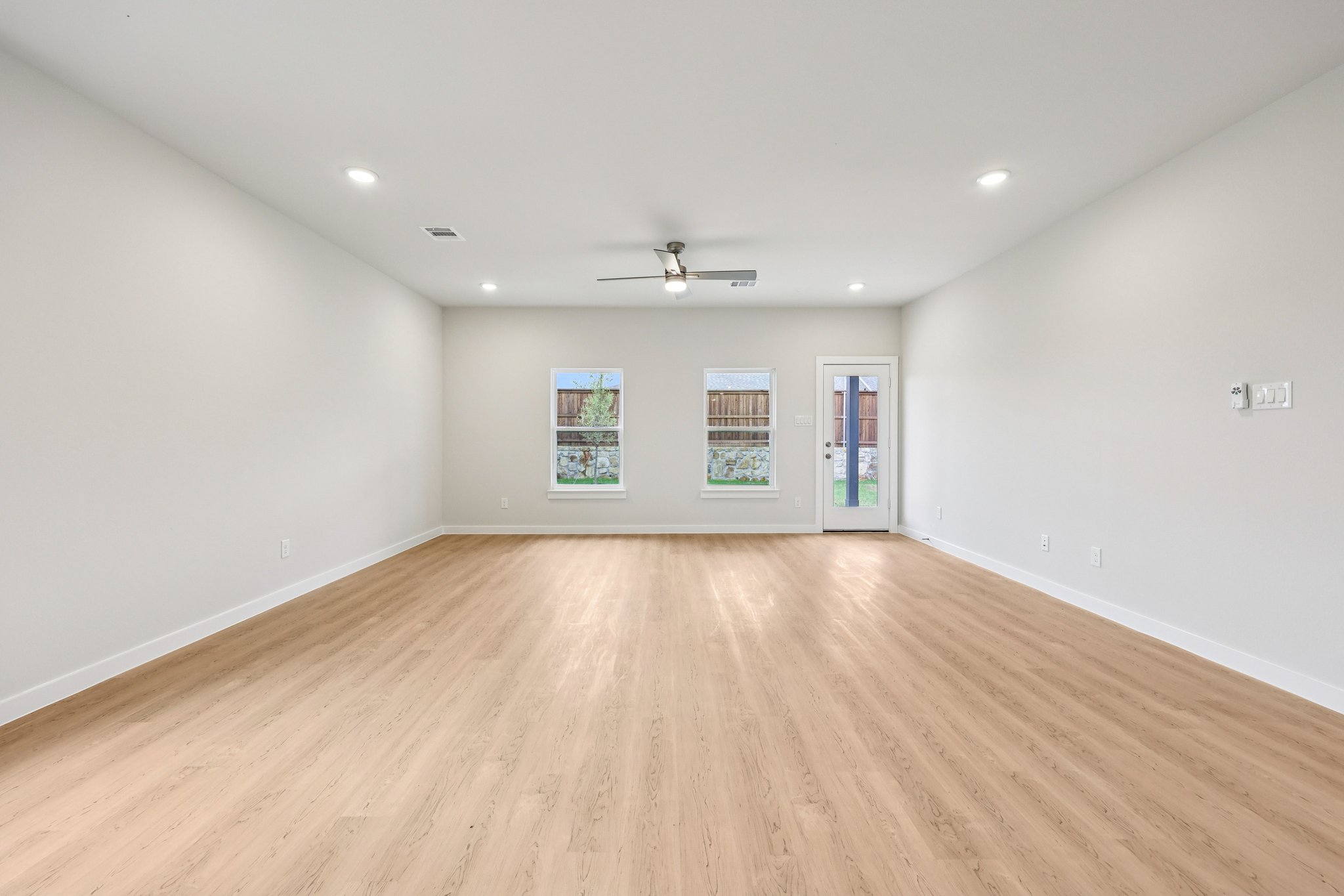 A room with a wood floor and a ceiling fan.