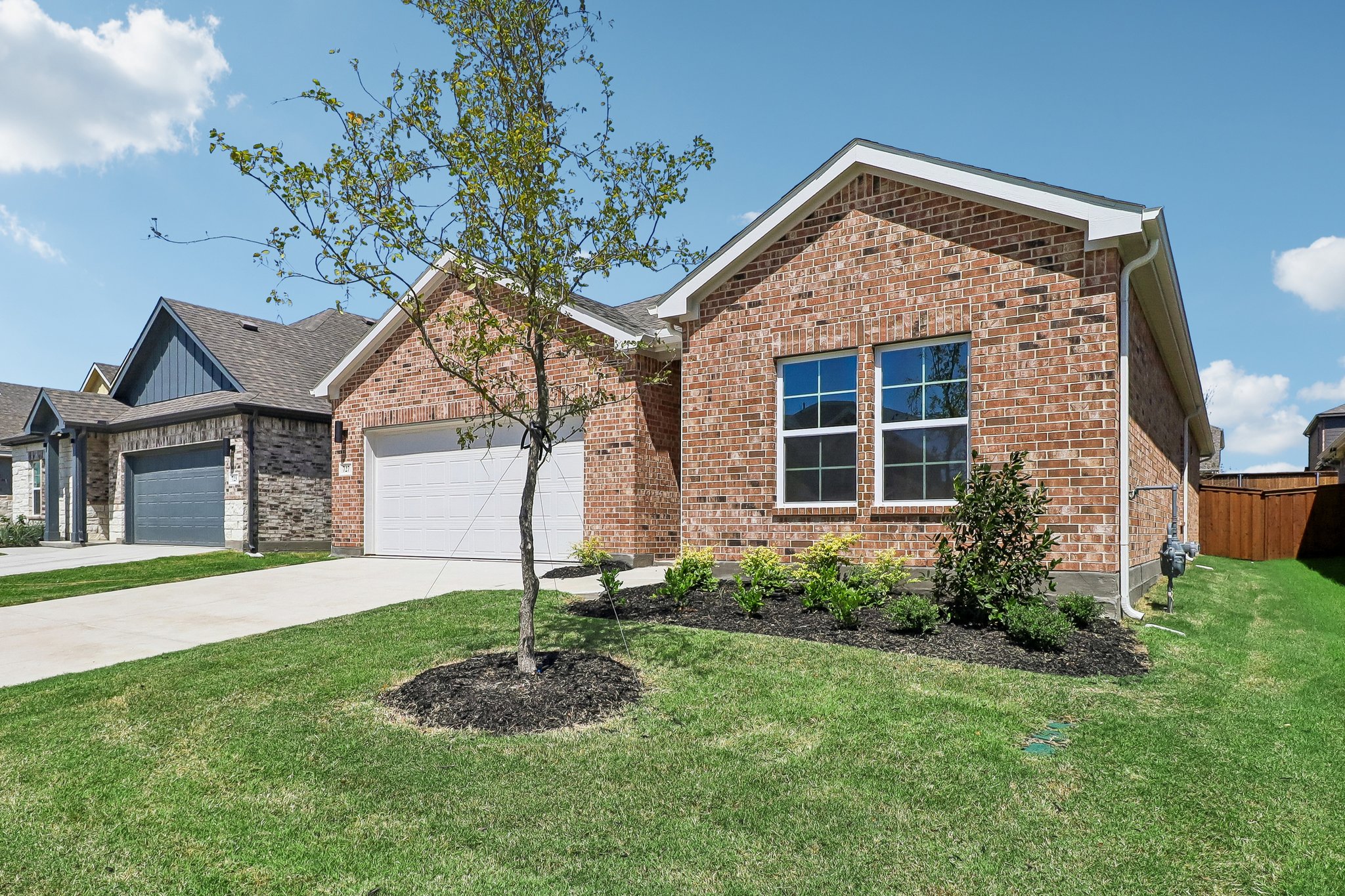 A brick house with a tree in the front yard.