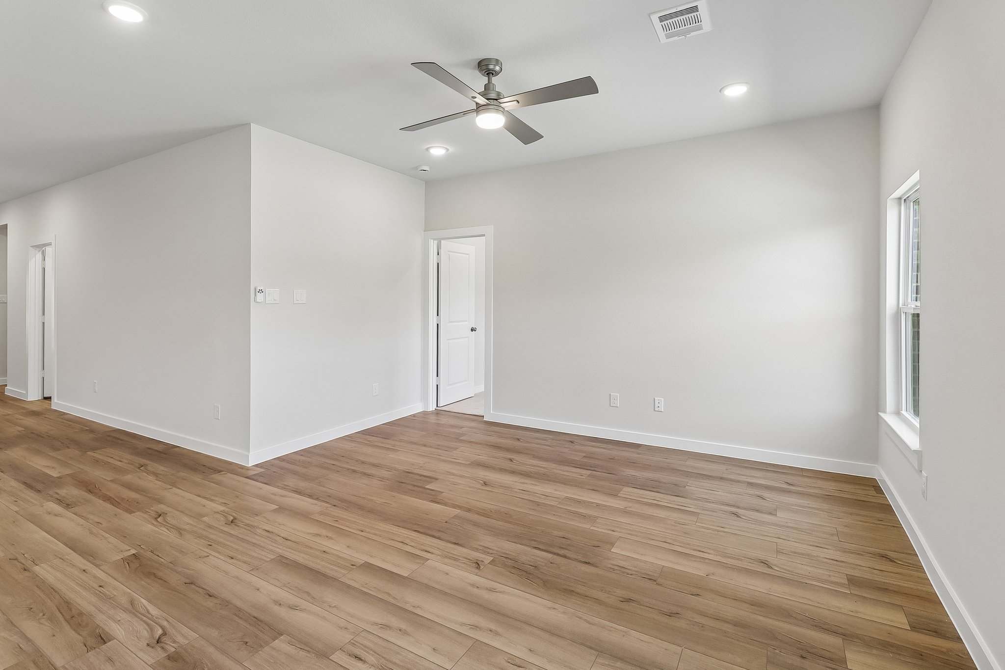 A room with a wood floor and a ceiling fan.