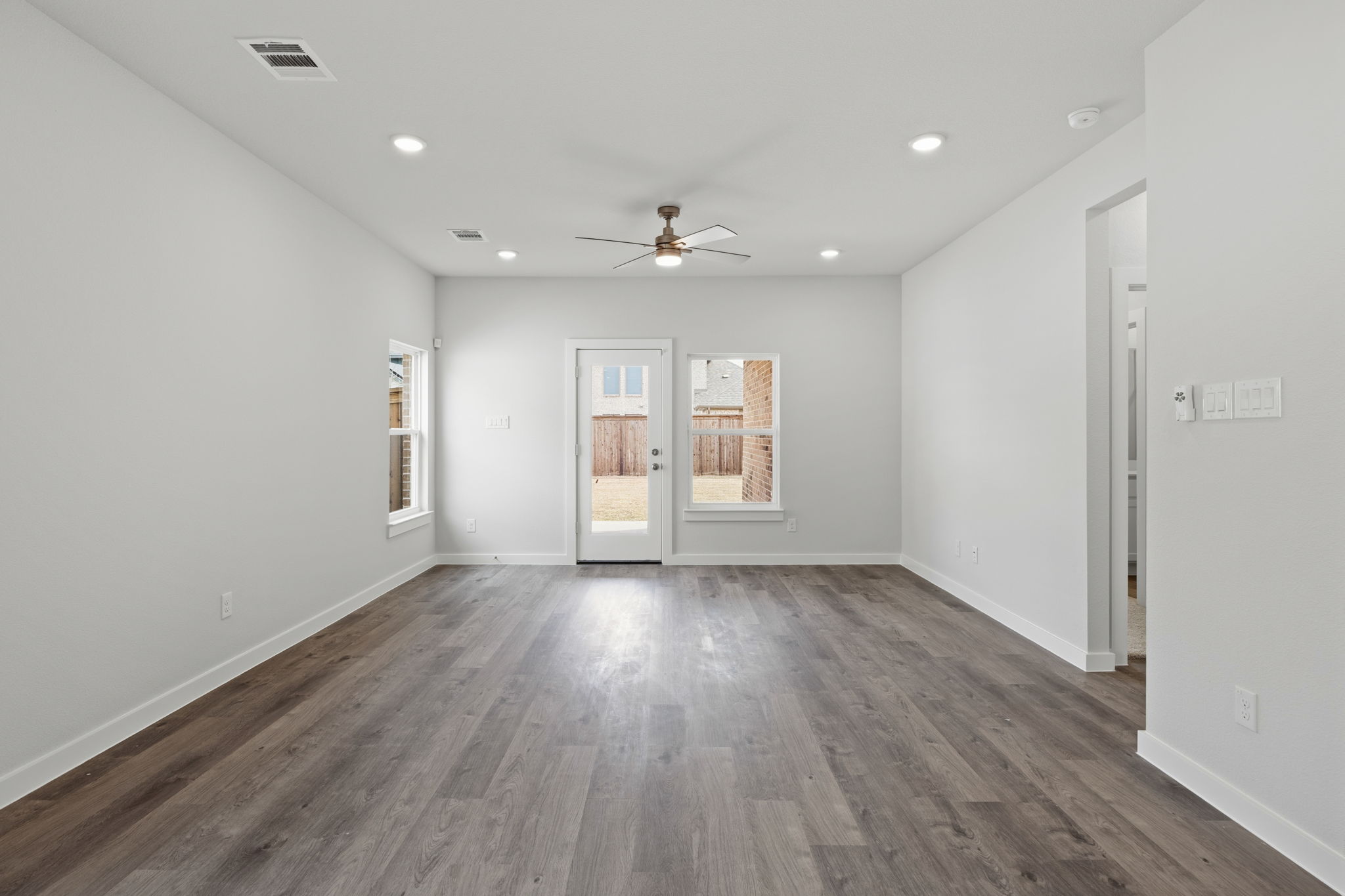 A room with a wood floor and a ceiling fan.