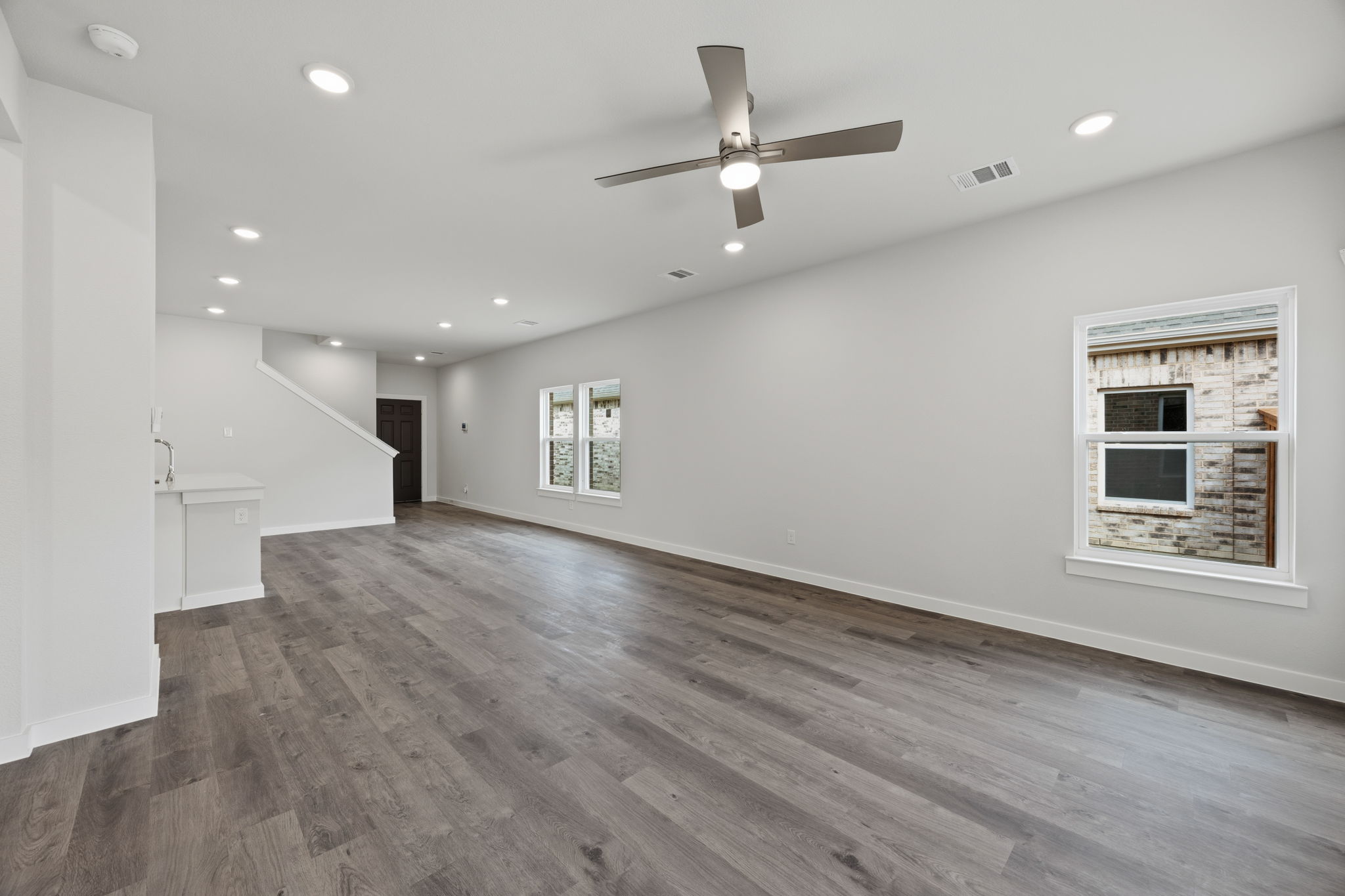 A large empty room with a wood floor and a ceiling fan.