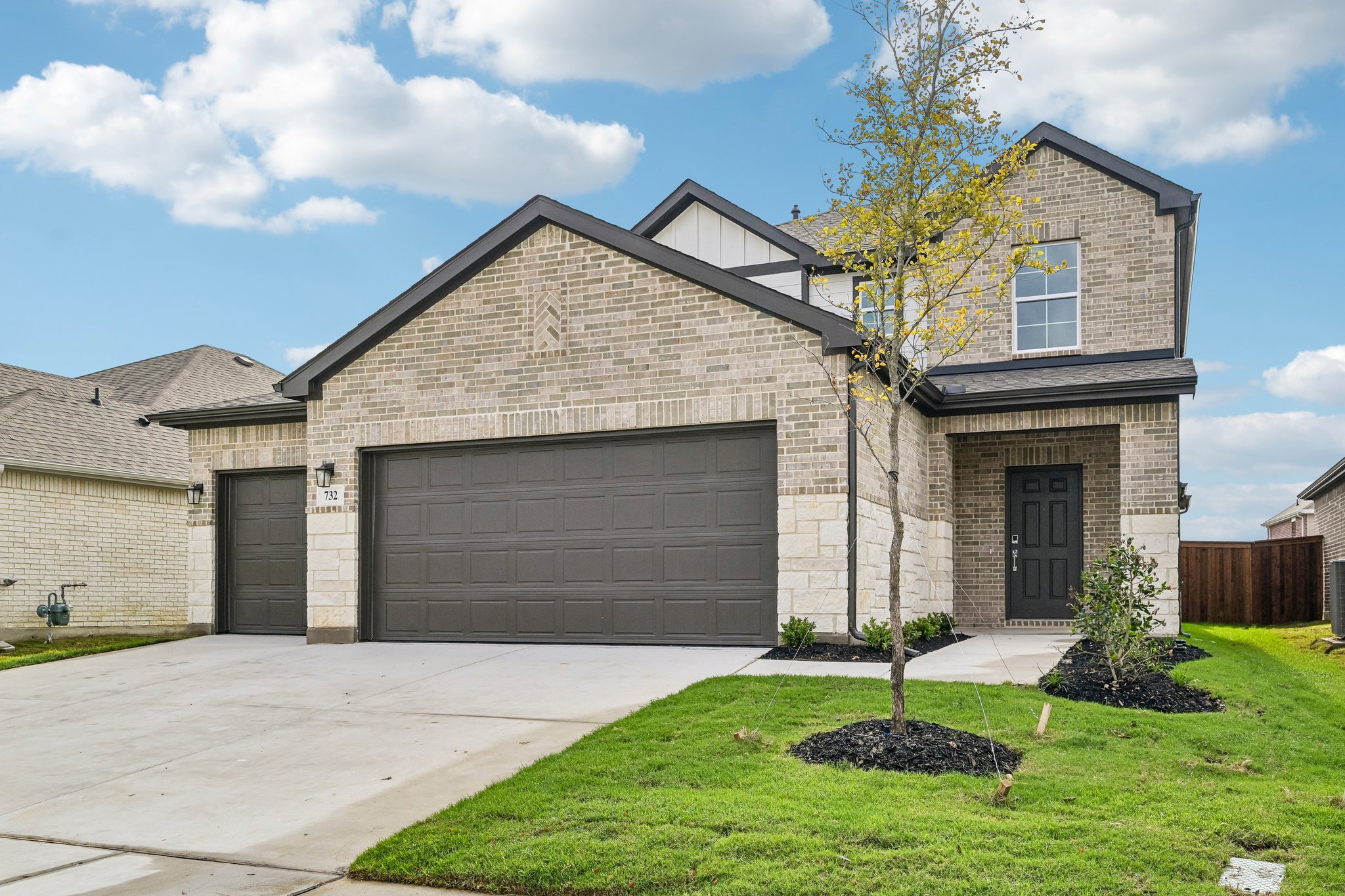 A house with a garage and a tree in the front.