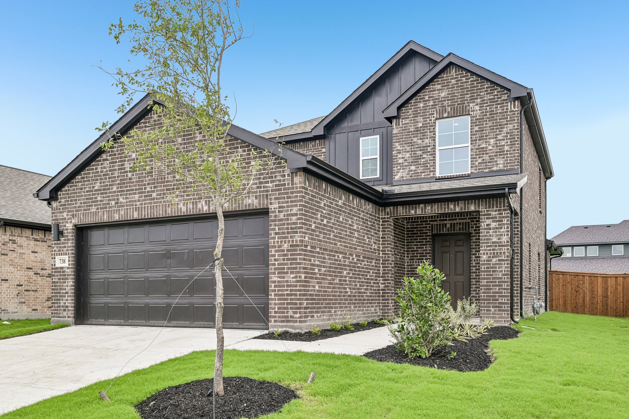 A brick house with a tree in the front yard.