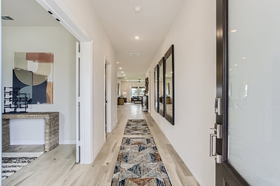 A hallway with a rug and a mirror.