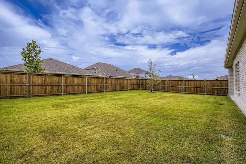 A fenced in yard with a house in the background.