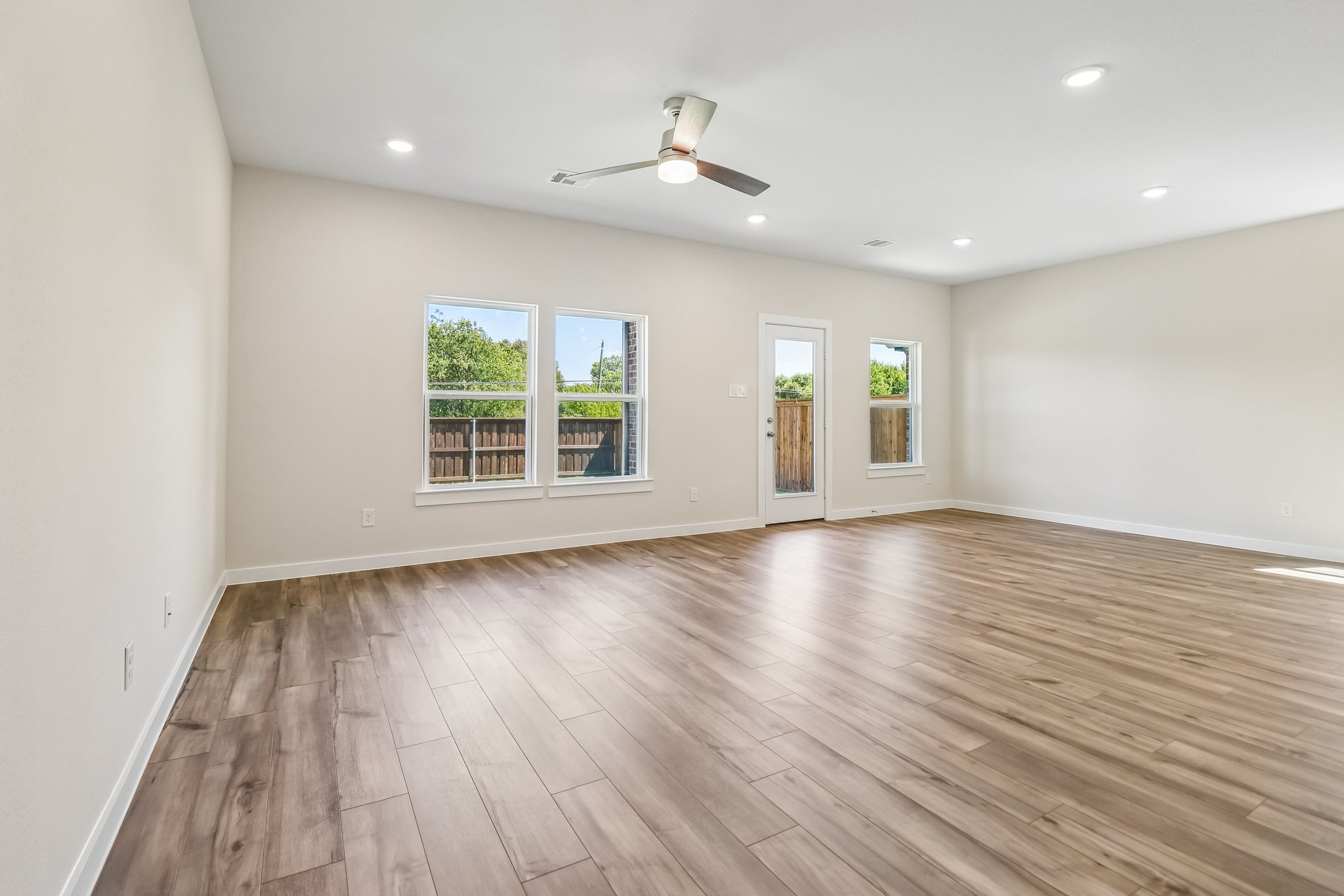 A room with a wood floor and a wood floor with a ceiling fan.