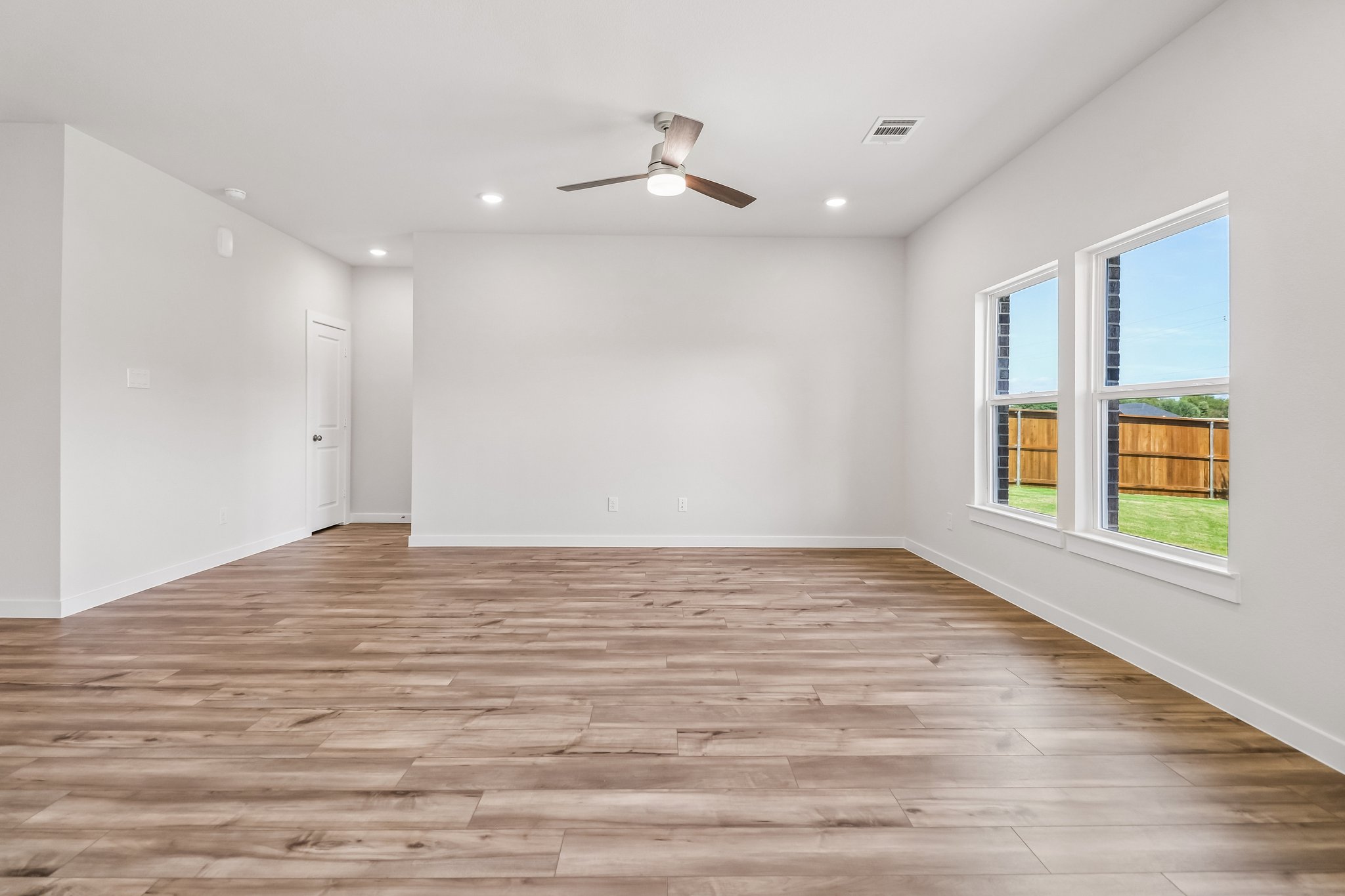 A room with a wood floor and a wood floor with a ceiling fan.