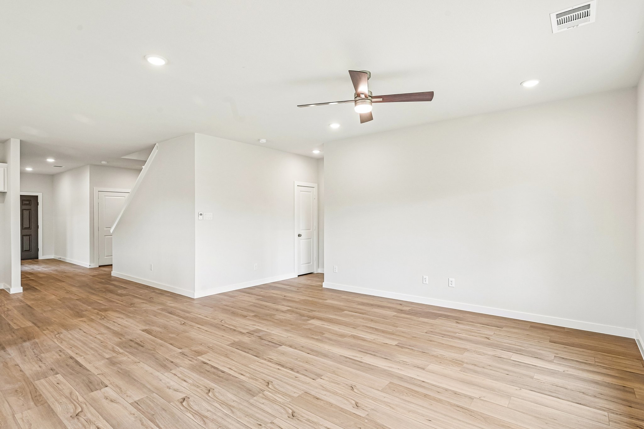 A room with a wood floor and a ceiling fan.