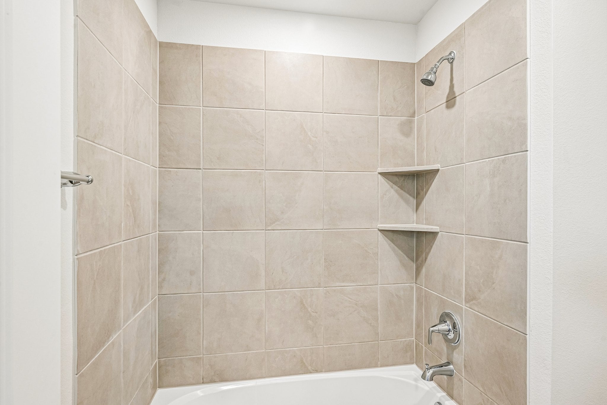A bathroom with a bathtub and shelves.