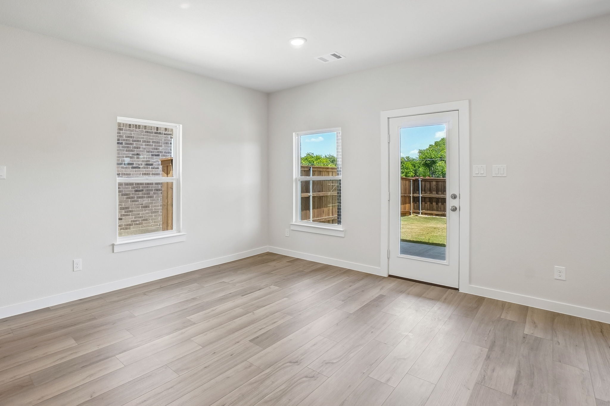 A room with windows and a wood floor.