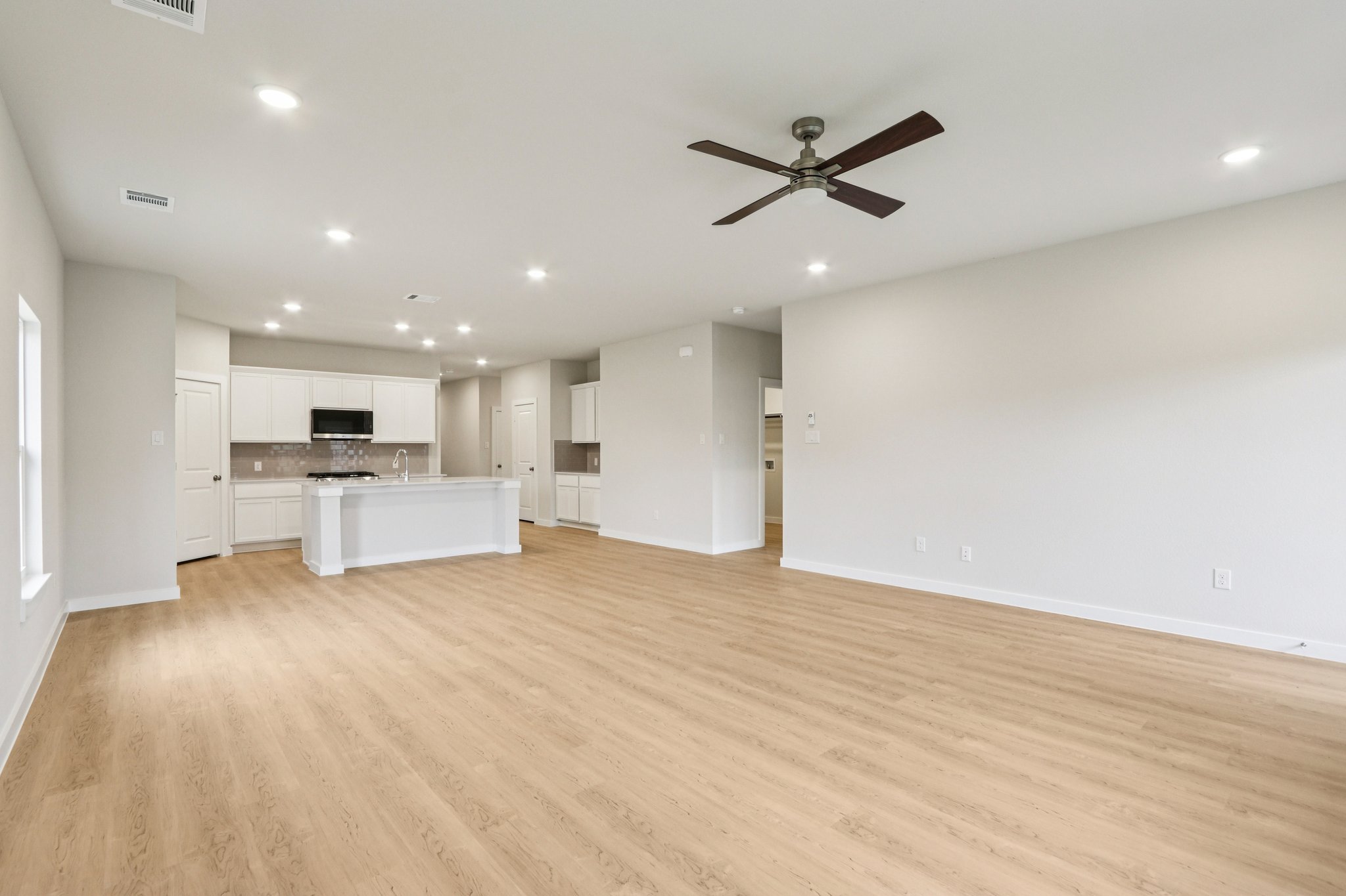 A large empty room with a wood floor and a ceiling fan.