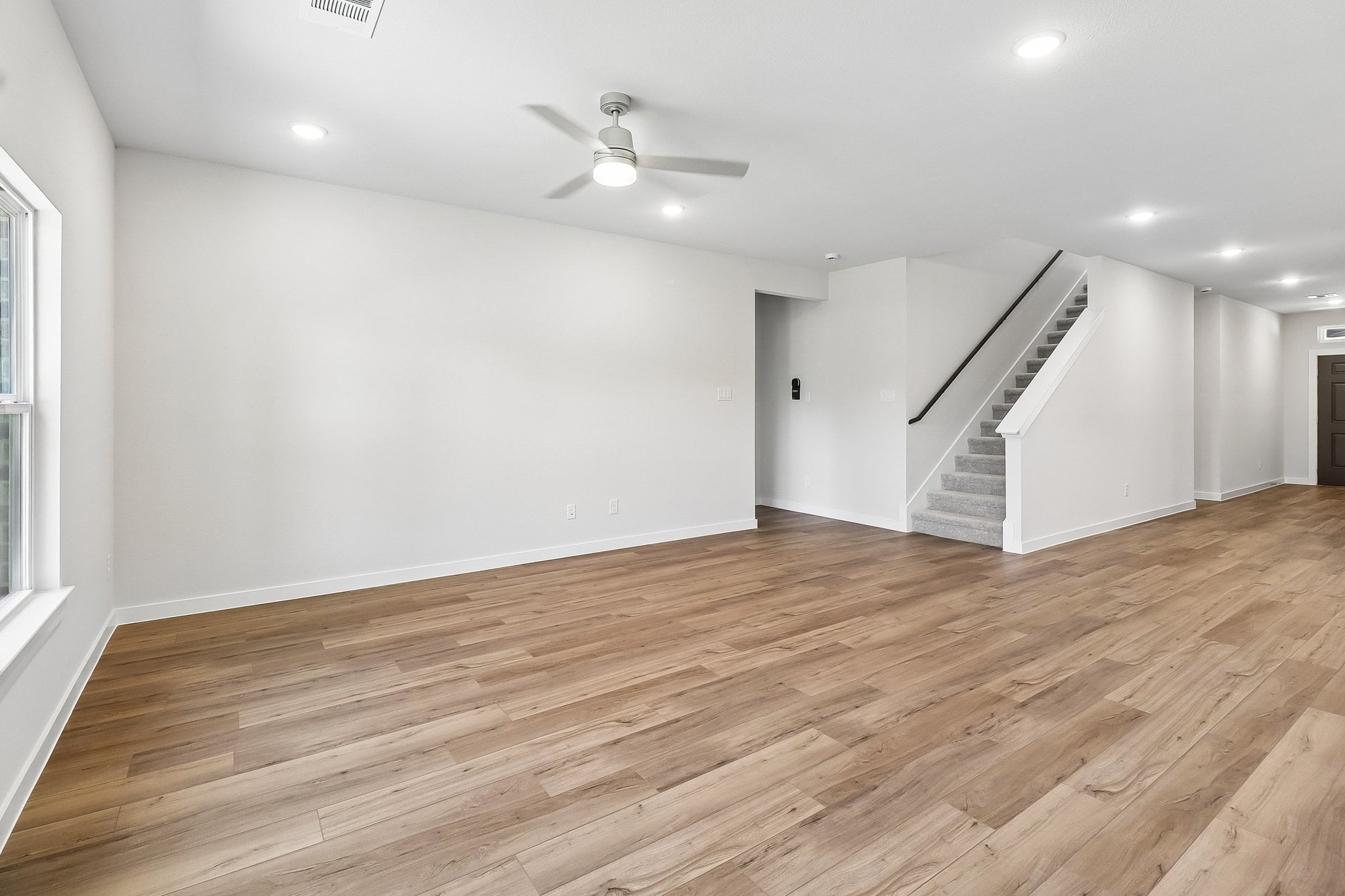 A room with a wood floor and a wood floor with a staircase.