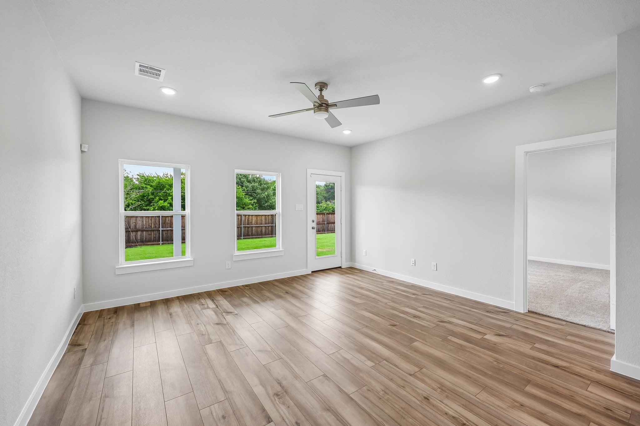 A room with a wood floor and a wood floor with a fan.