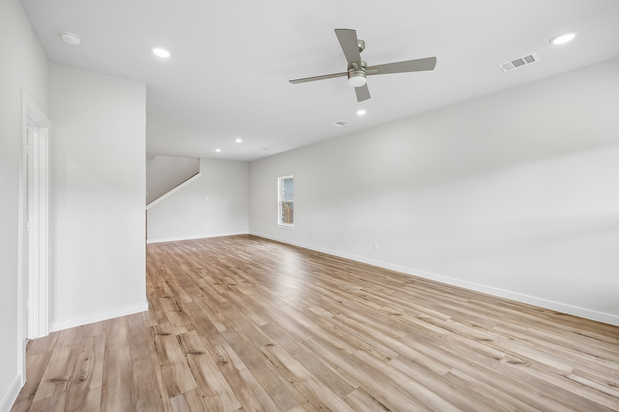 A room with a wood floor and a ceiling fan.
