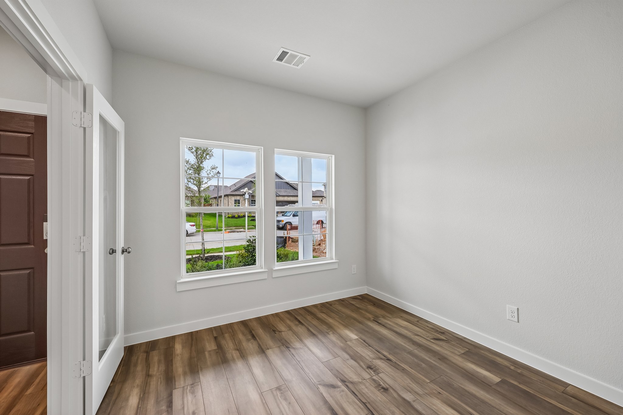 A room with a wood floor and a wood floor with a window.
