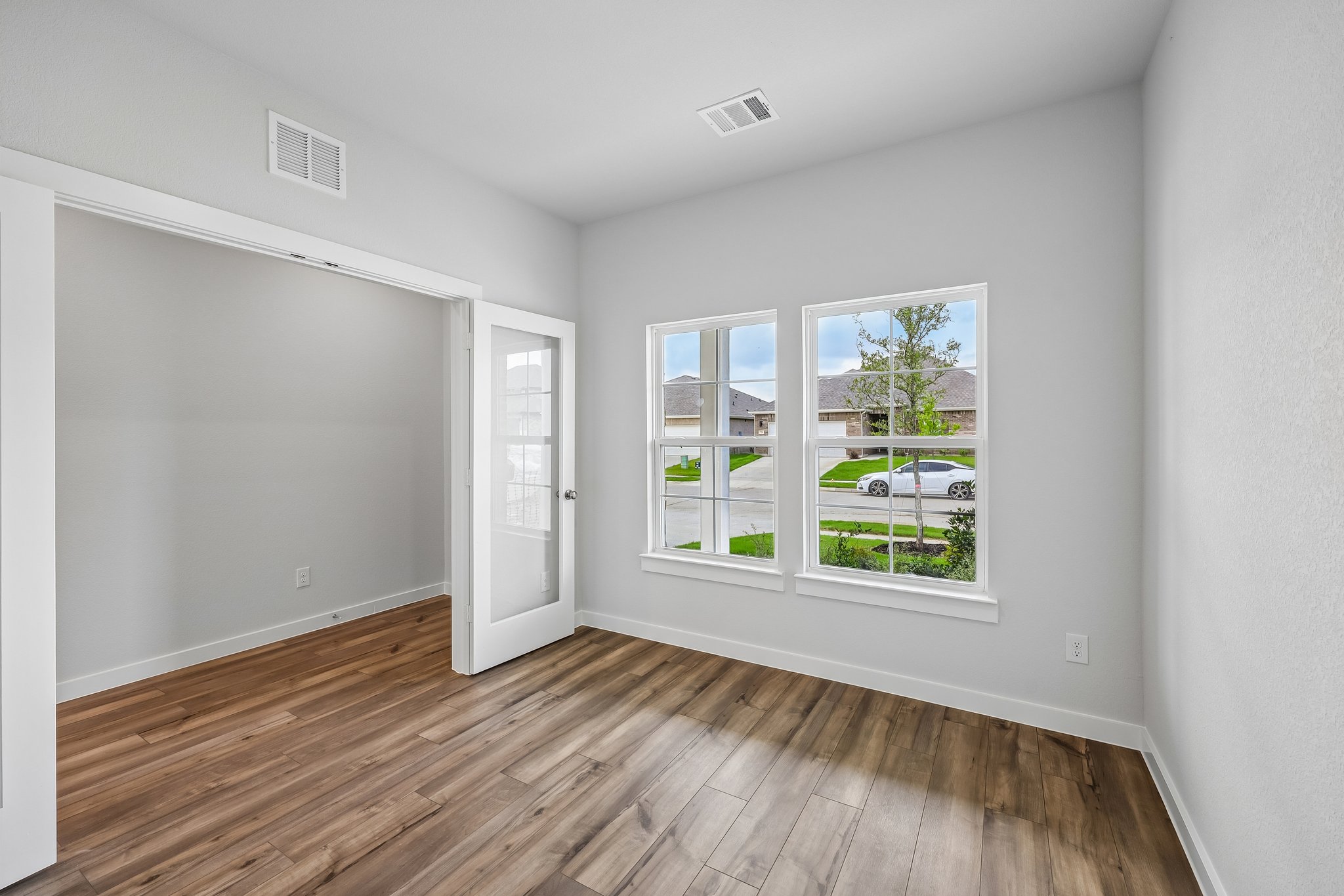 A room with a wood floor and a window with a wood floor.
