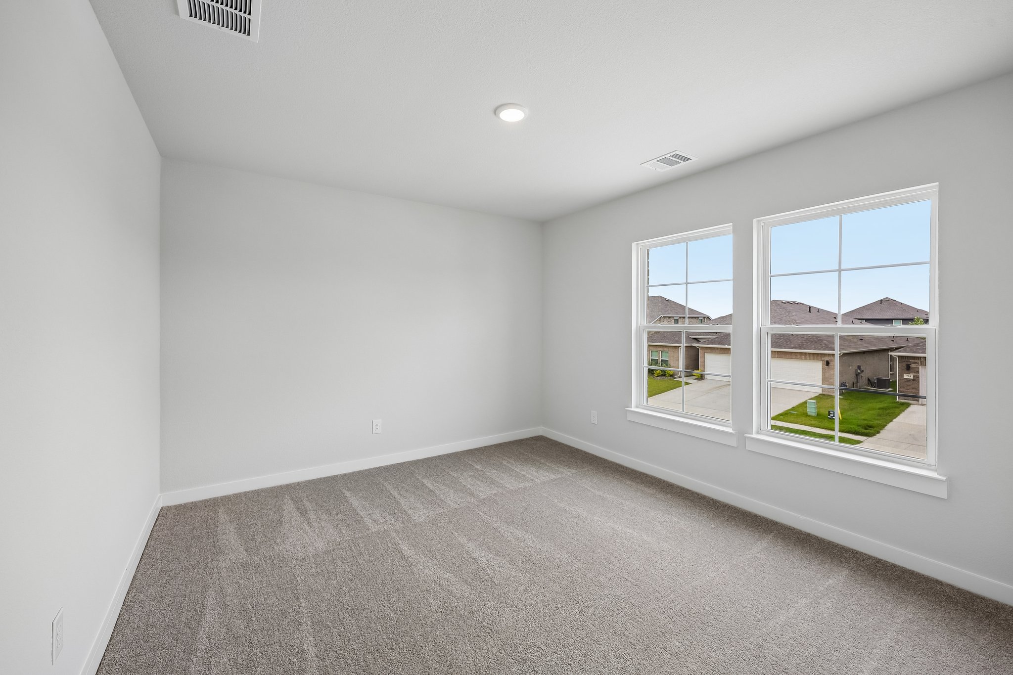 A room with windows and a green lawn outside.