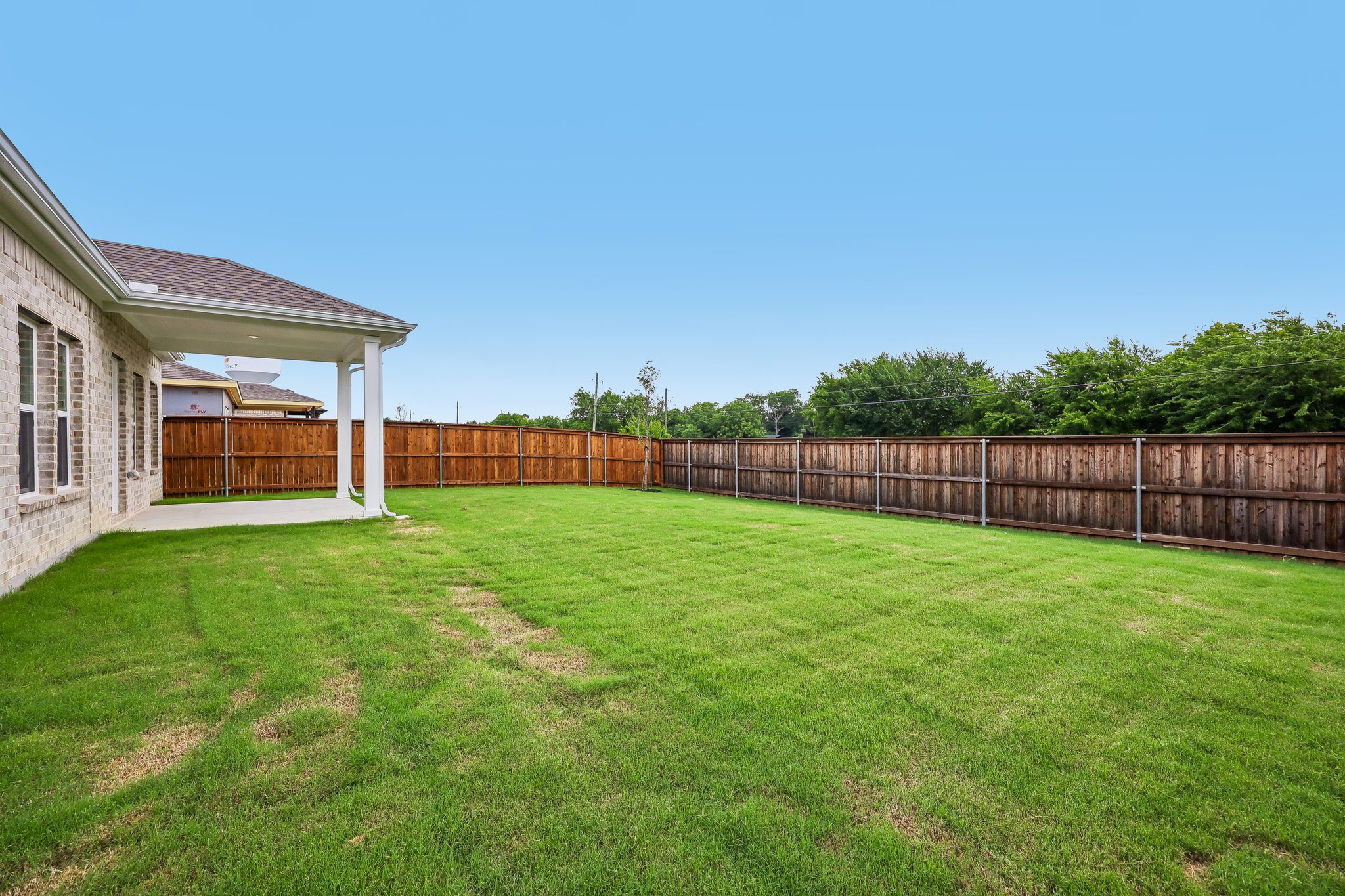A fenced in yard with a house and trees in the background.
