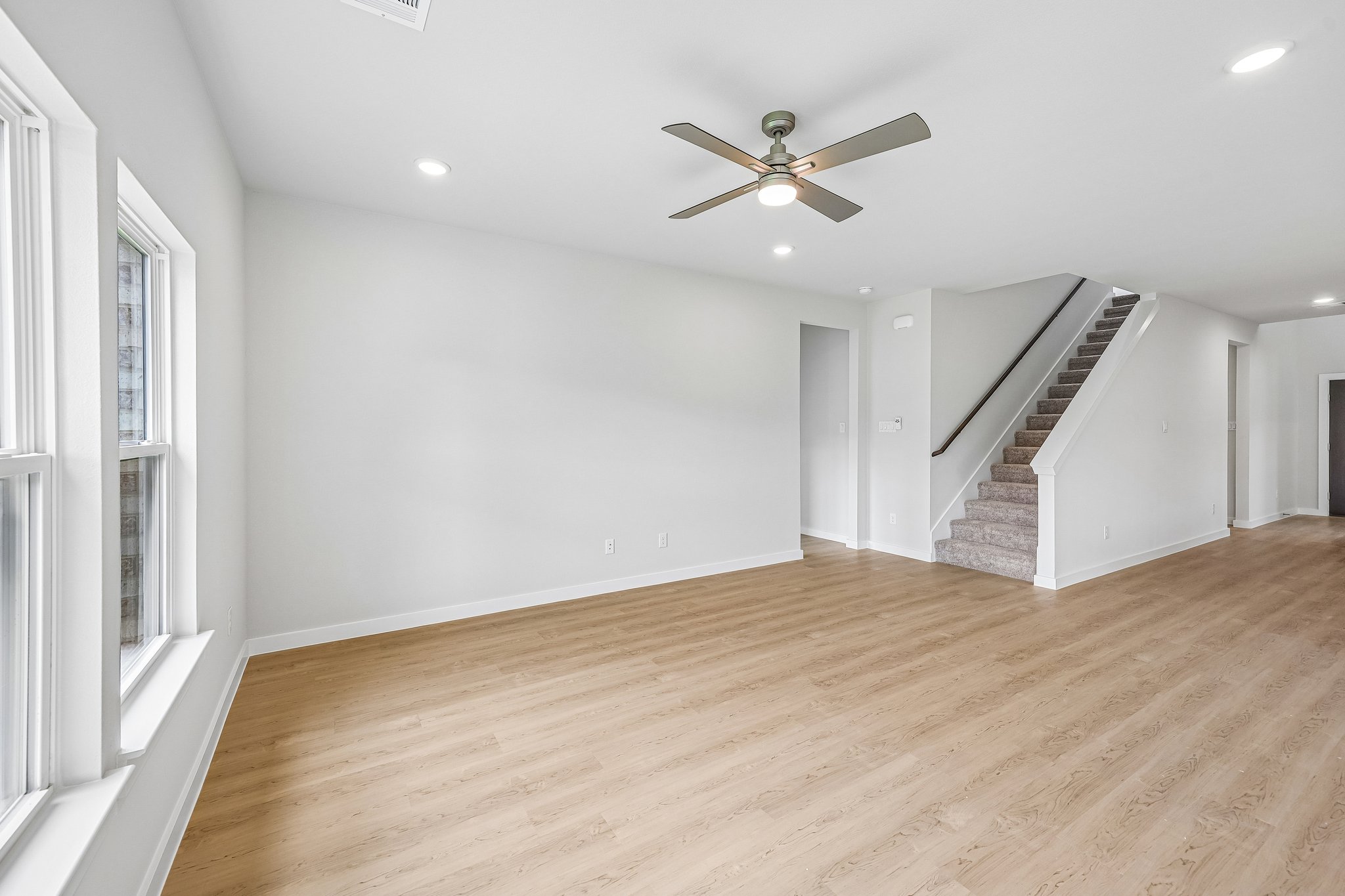 A room with a wood floor and a wood floor with a ceiling fan.