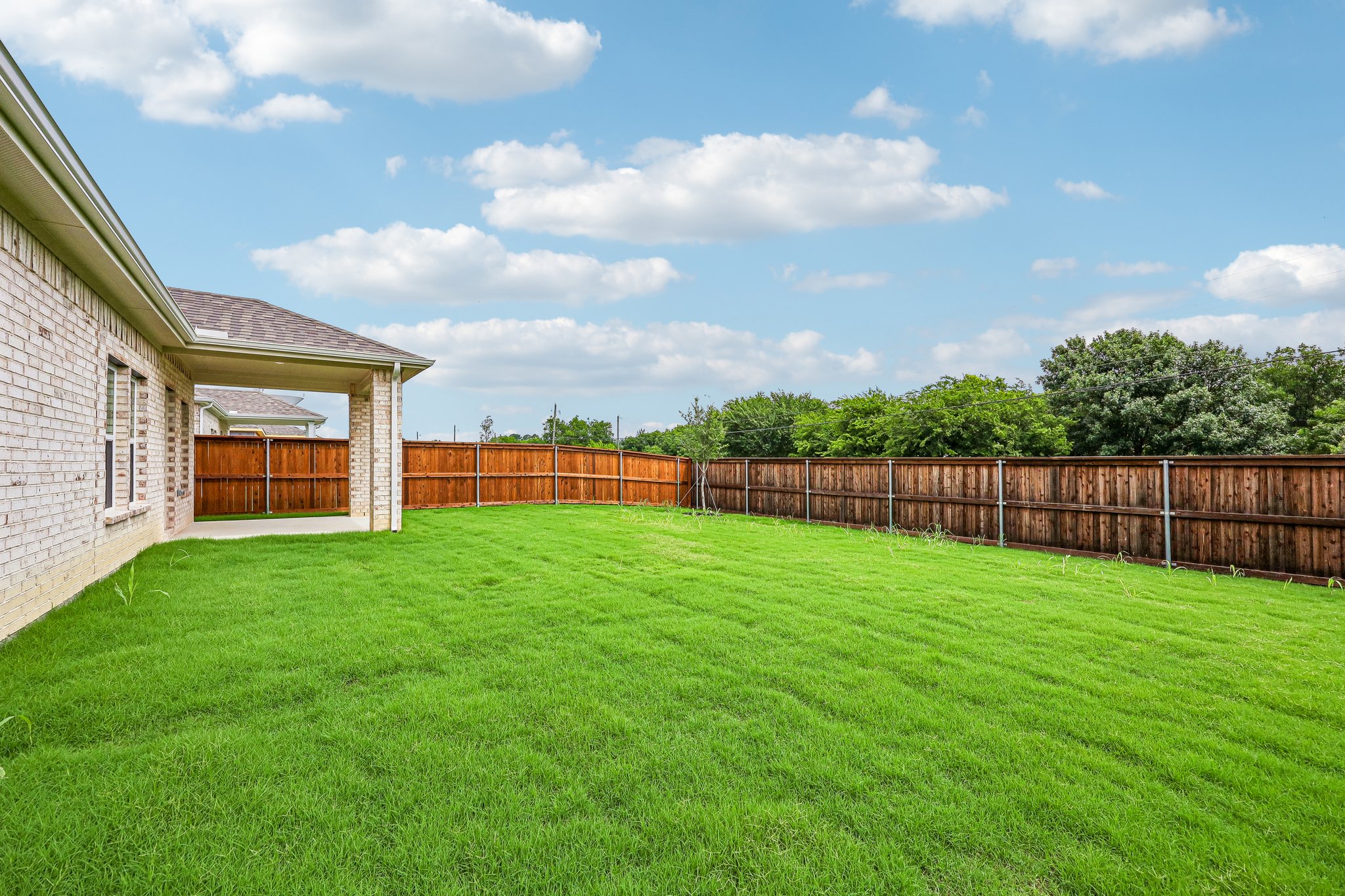 A fenced in yard with a house and trees in the background.