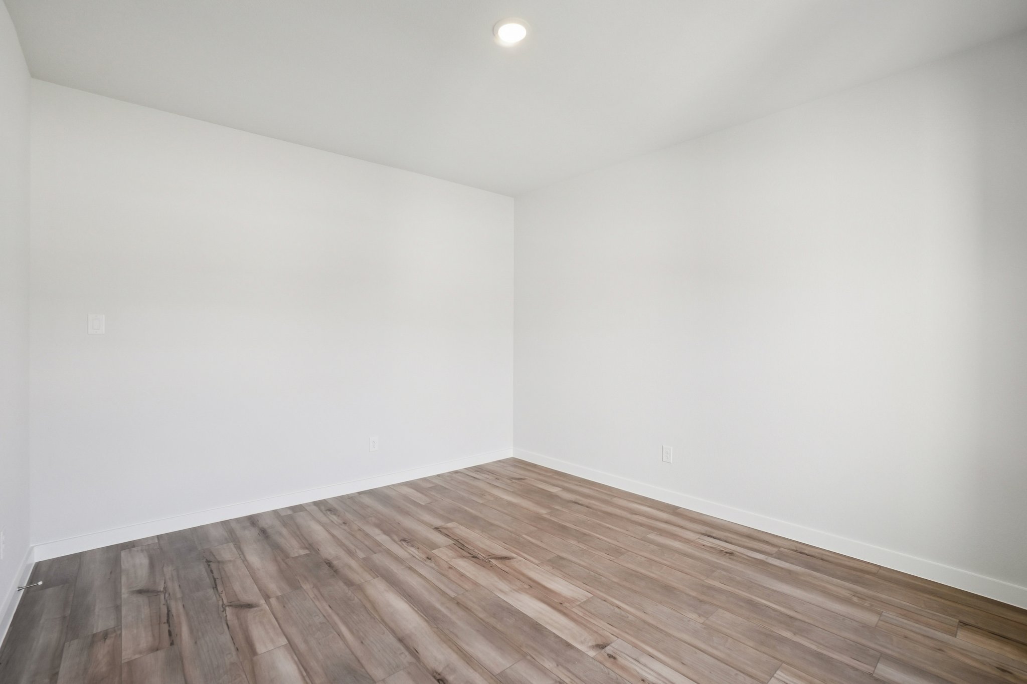 A room with a wood floor and a light on the wall.