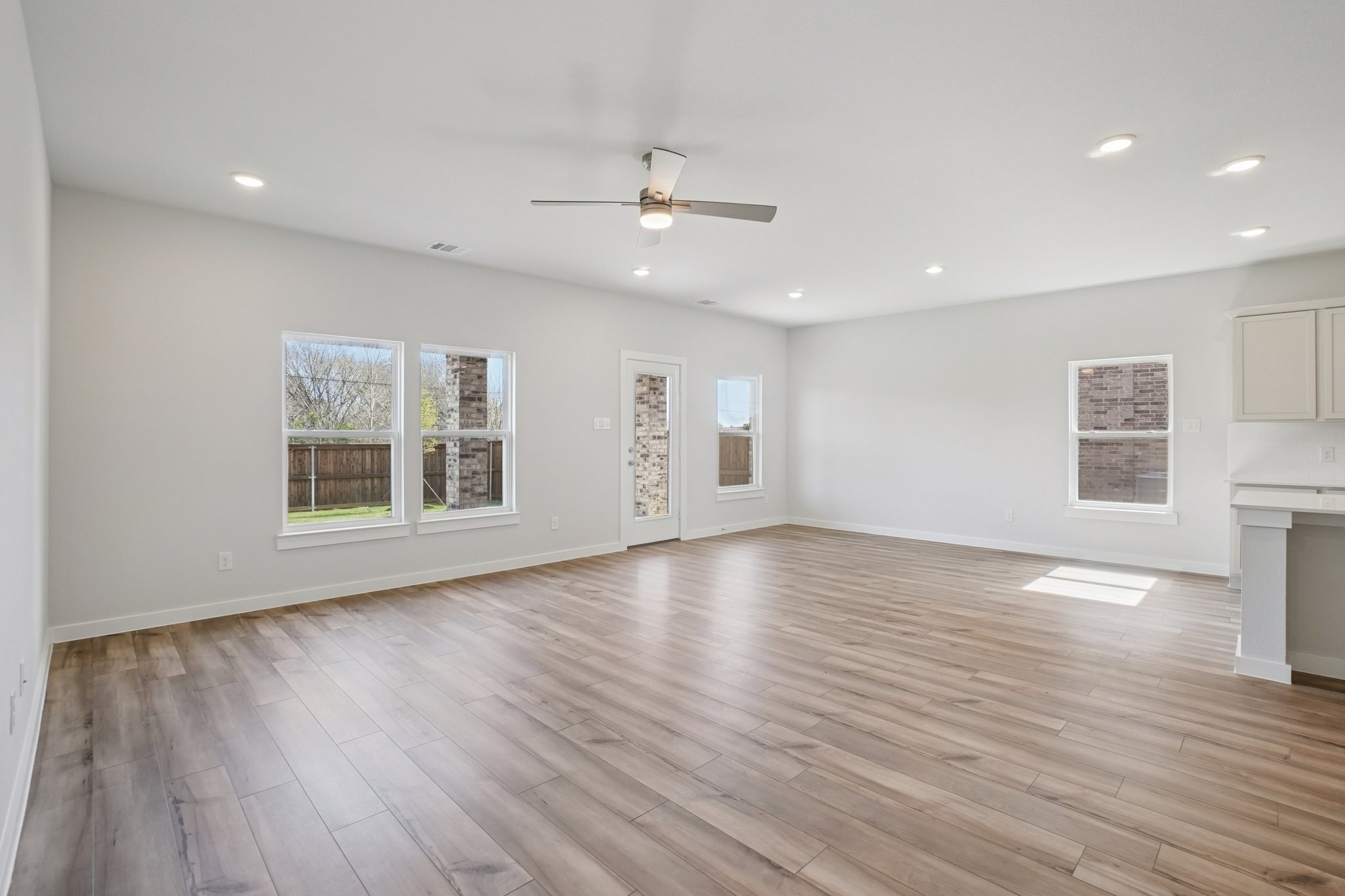 A large empty room with a wood floor and a ceiling fan.