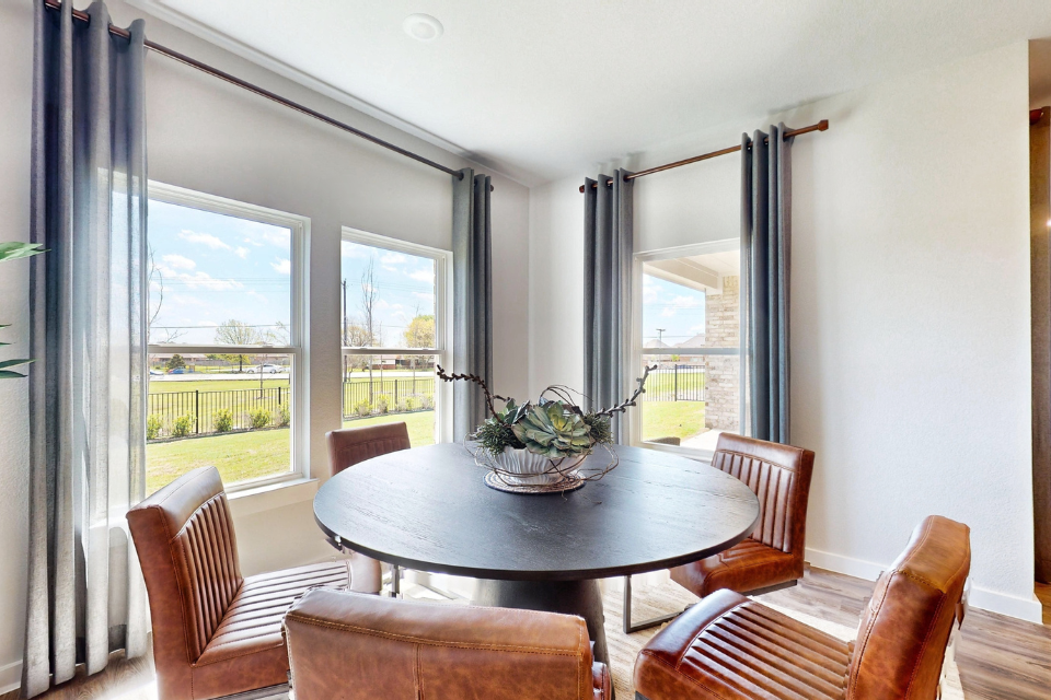 A dining room table with chairs and a large window with a view of the city.