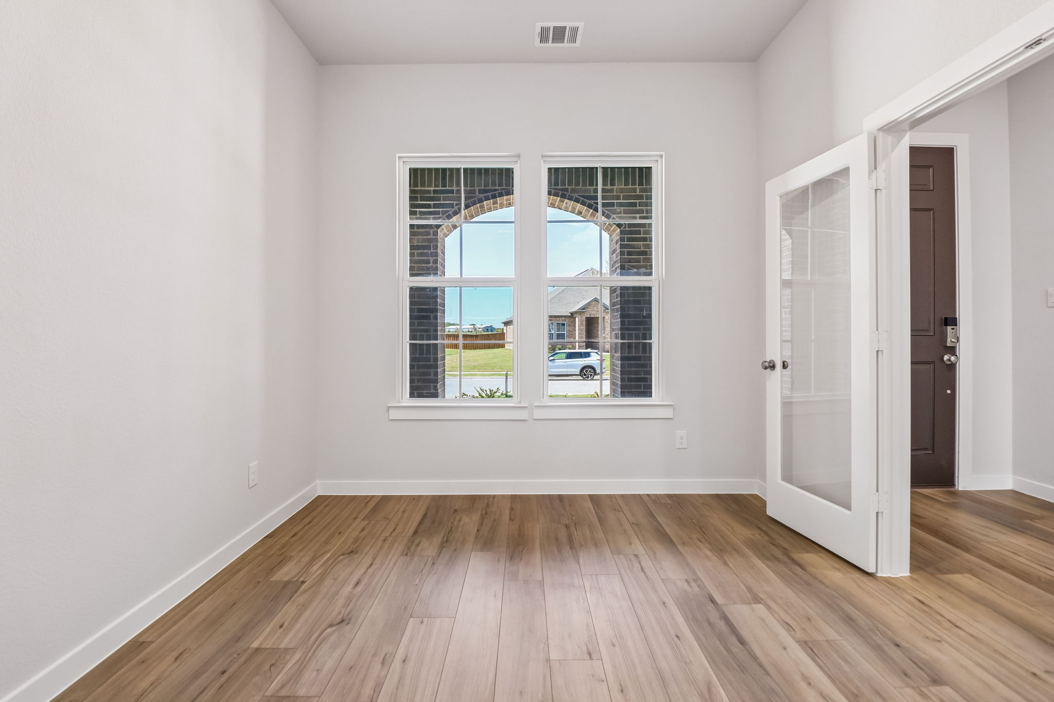 A room with a window and a wood floor.