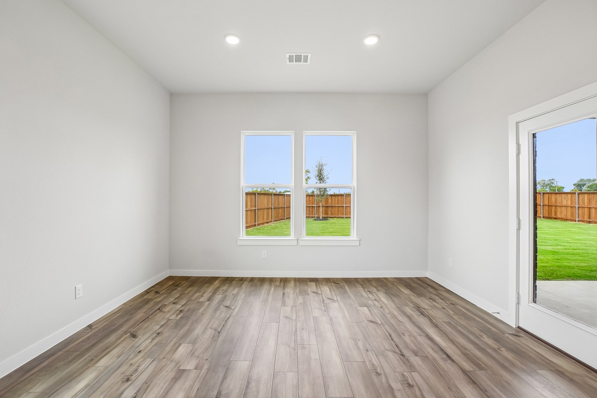 A room with a wood floor and windows.