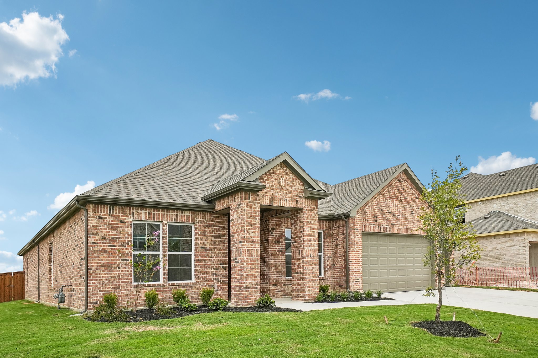 A brick house with a green lawn.