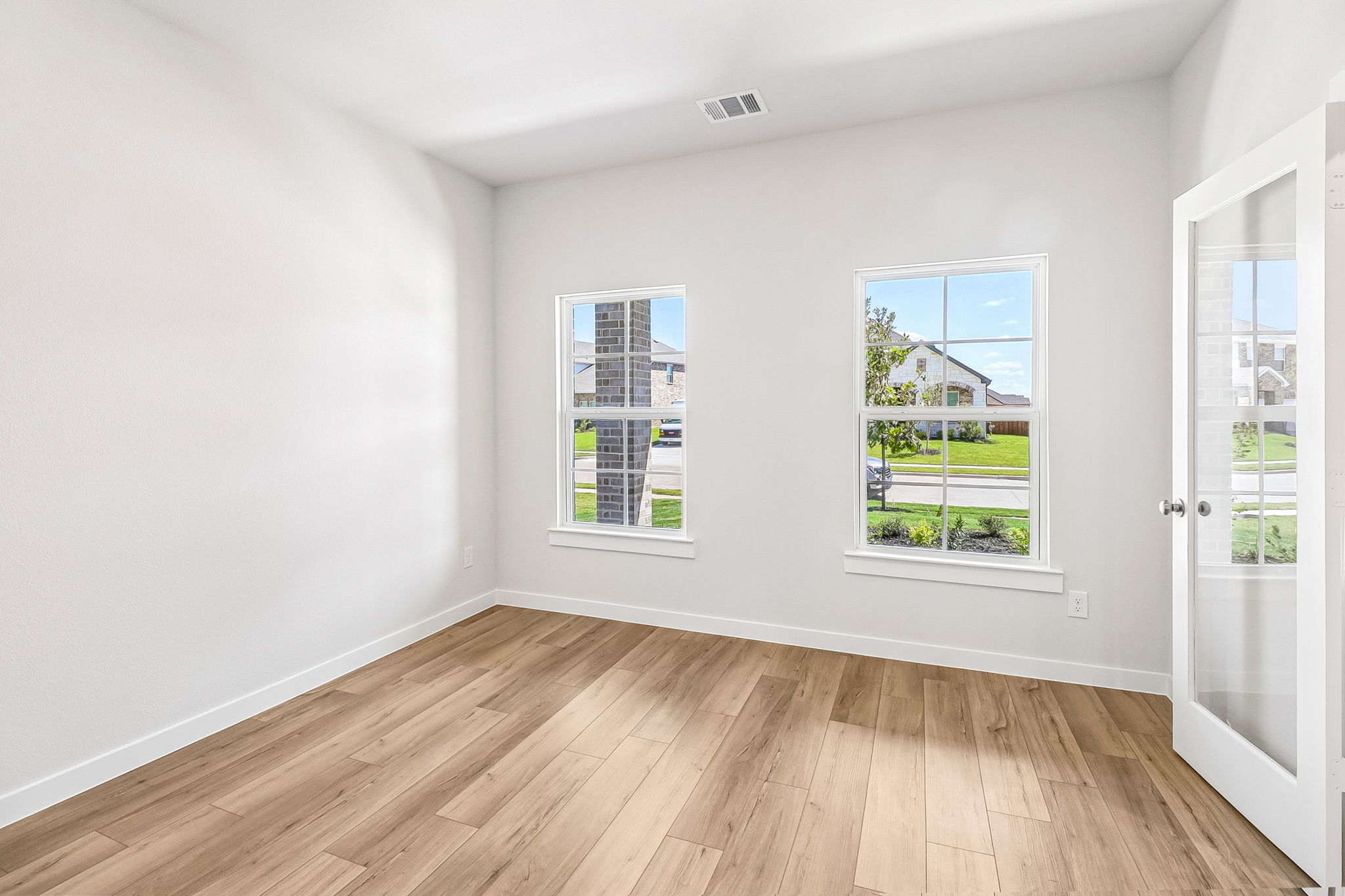 A room with windows and a wood floor.