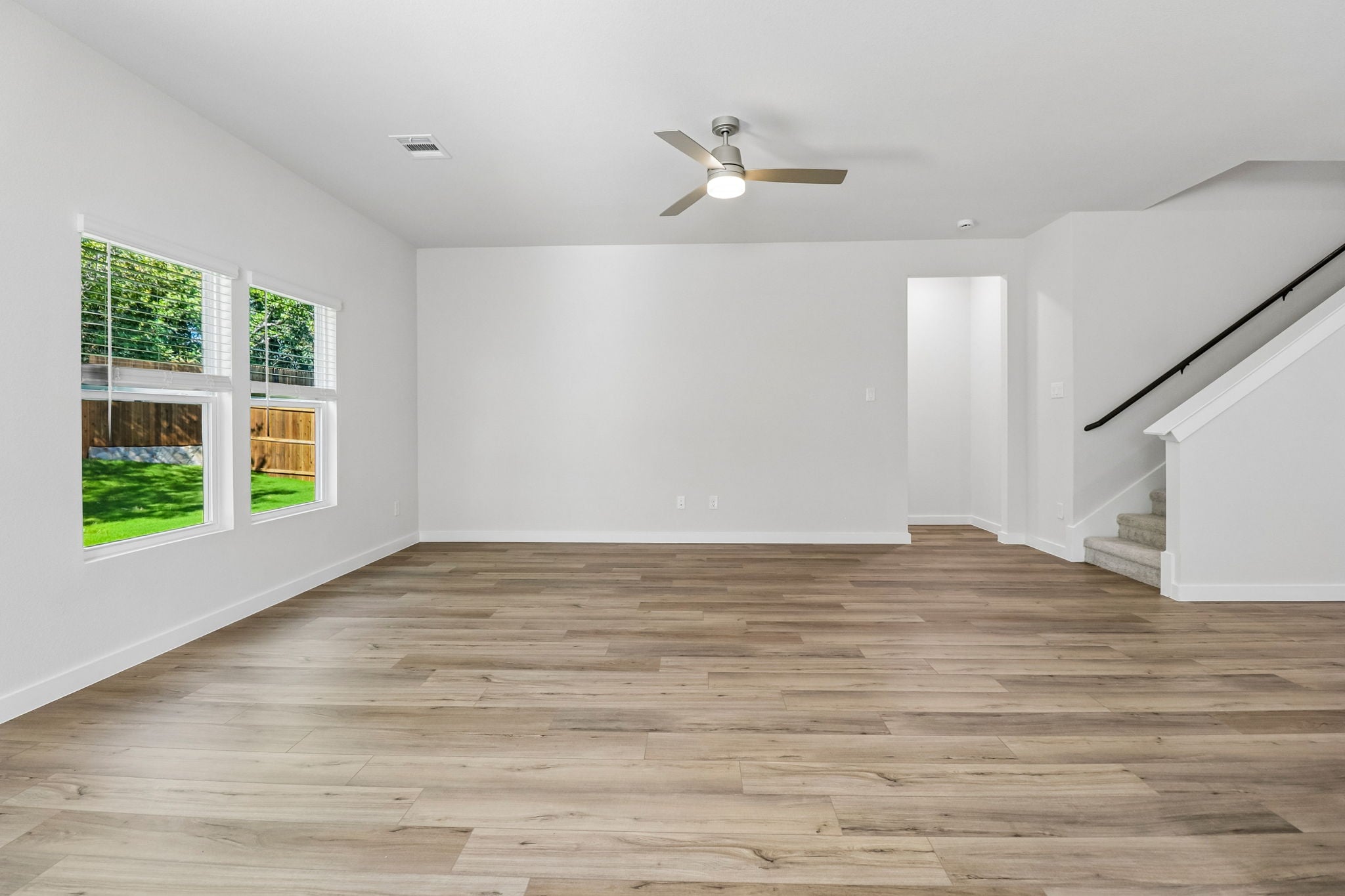 A room with a wood floor and a wood floor with a ceiling fan.