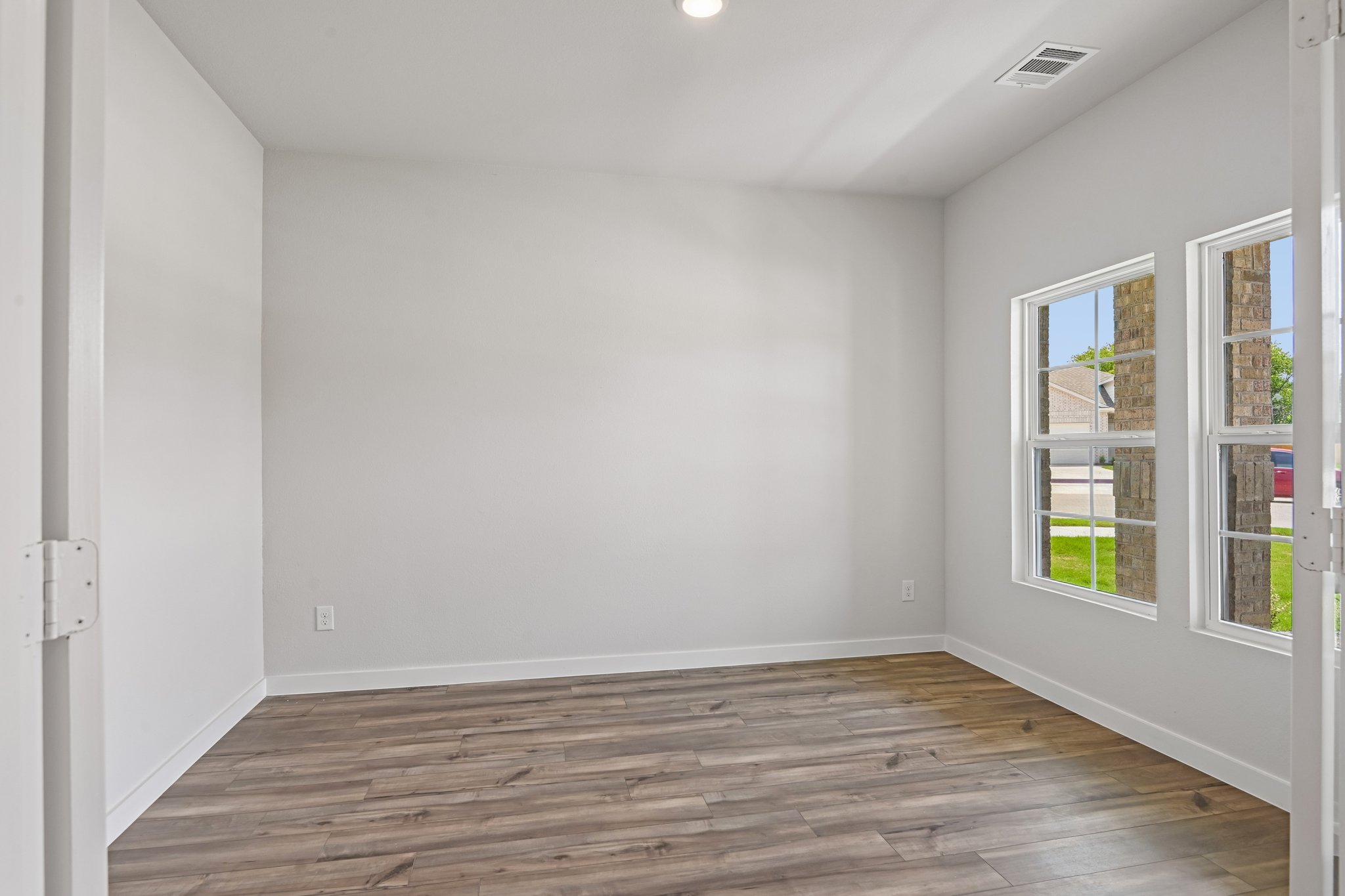 A room with a wood floor and windows.