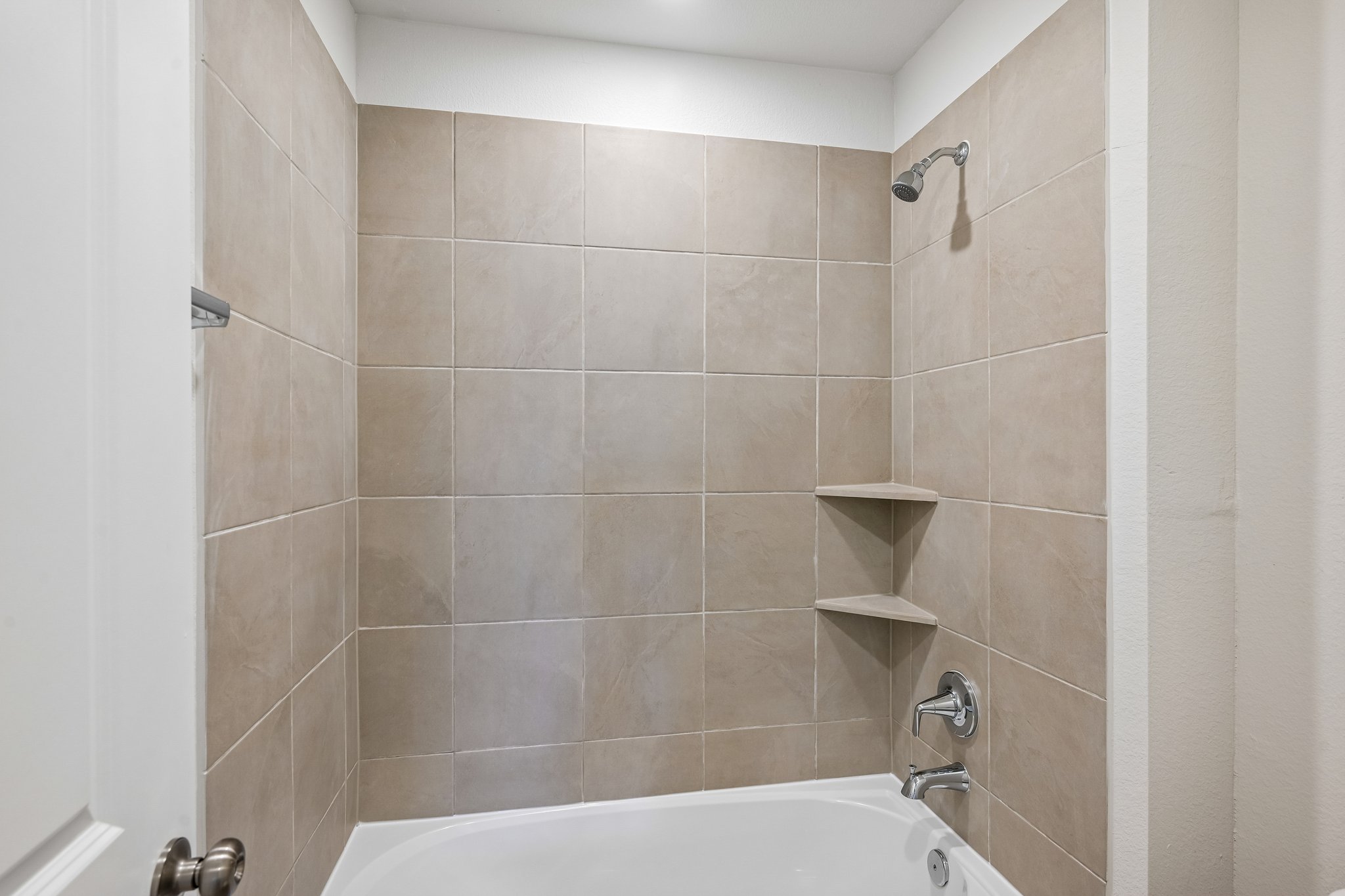 A bathroom with a bathtub and shelves.