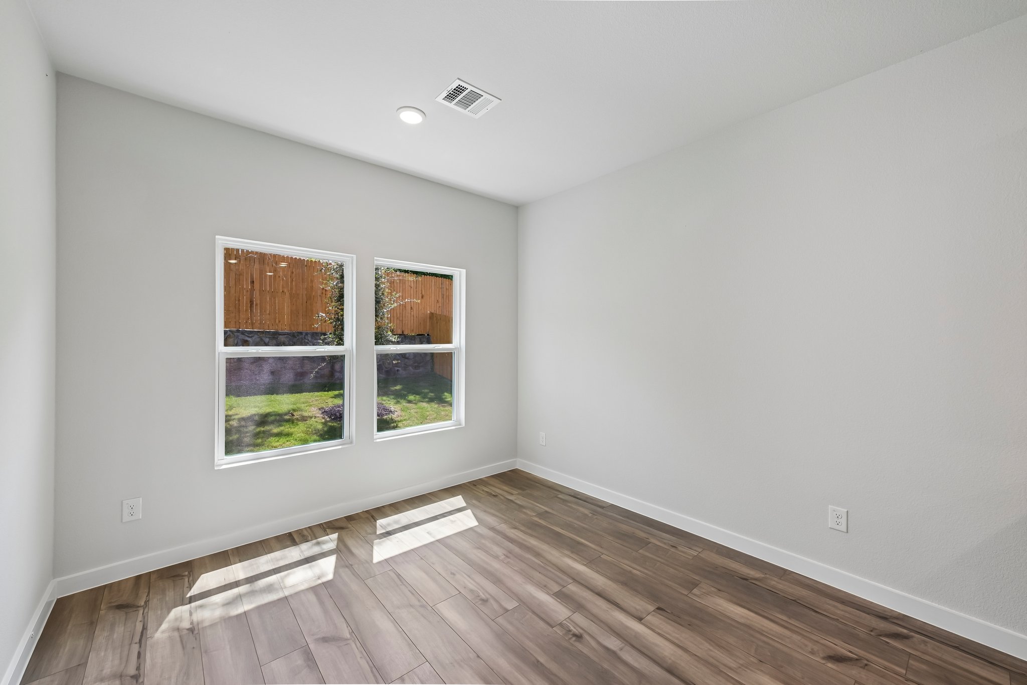 A room with a wood floor and windows.