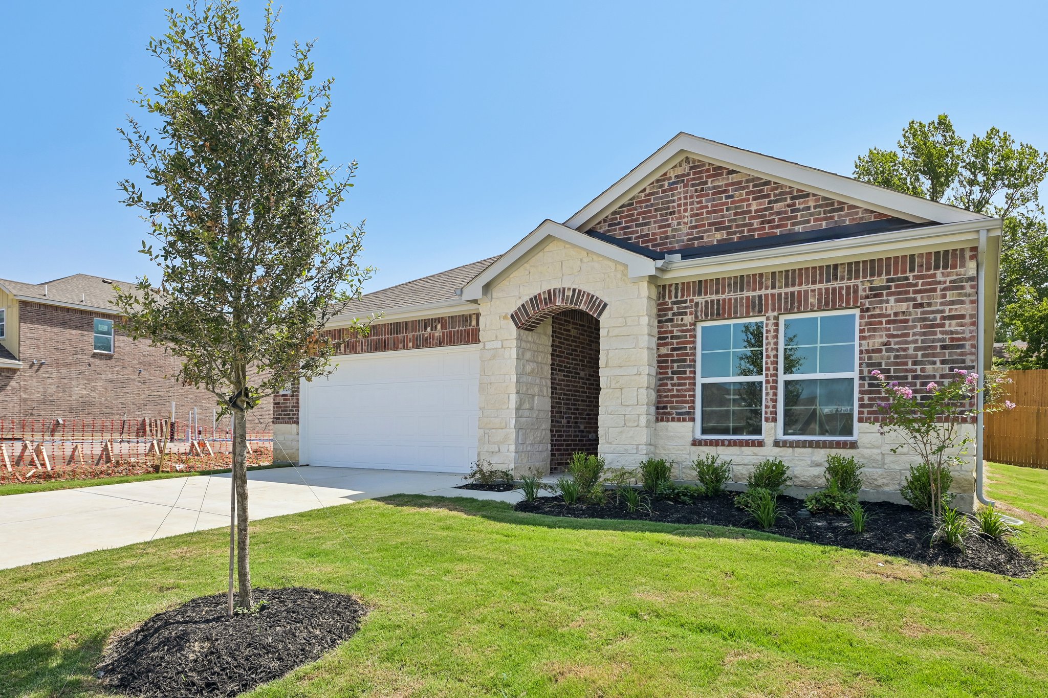 A brick house with a tree in the front yard.