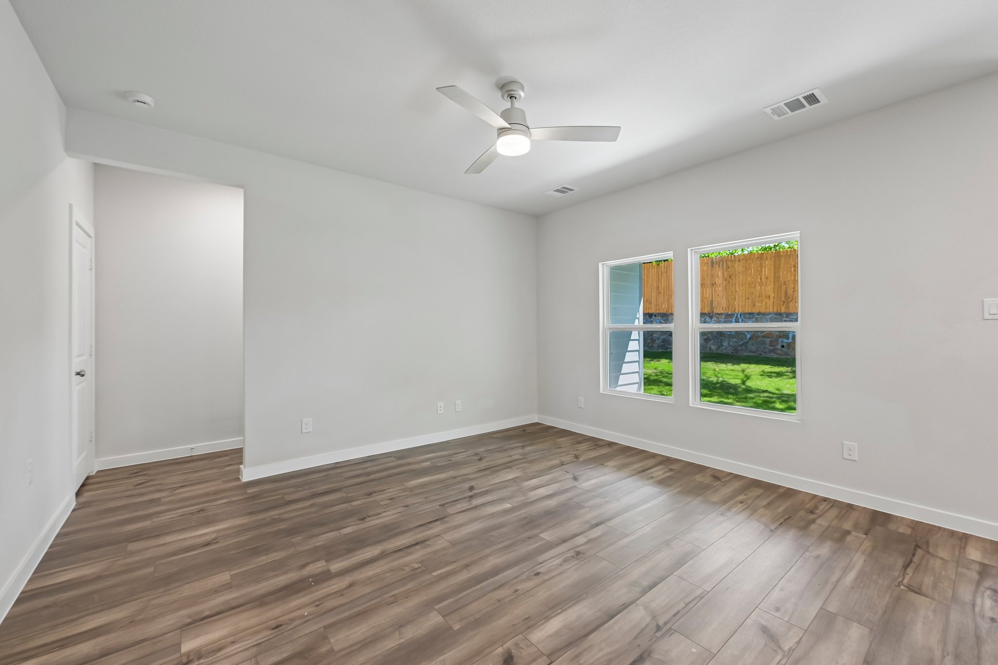 A room with a wood floor and a ceiling fan.