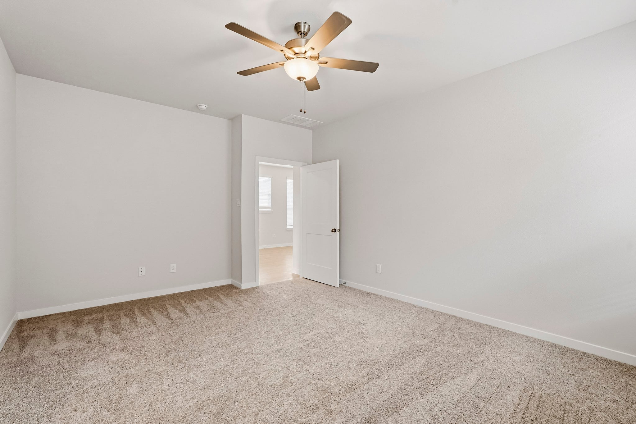 A room with a ceiling fan and a door.