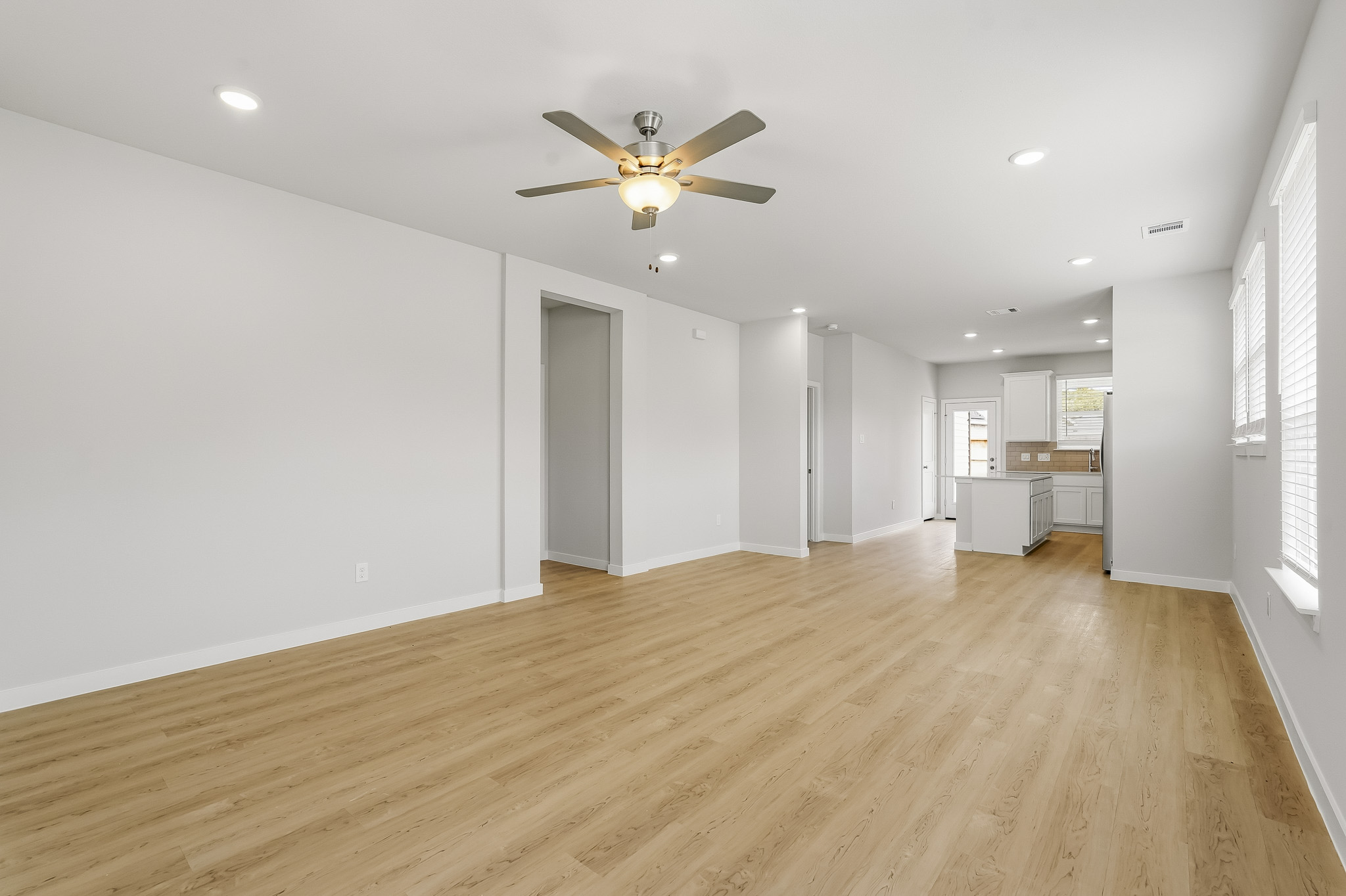 A large empty room with a ceiling fan and a wood floor.